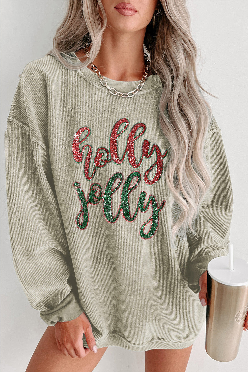 A vibrant green corded sweatshirt featuring a sequined 'holly jolly' graphic, perfect for festive occasions.