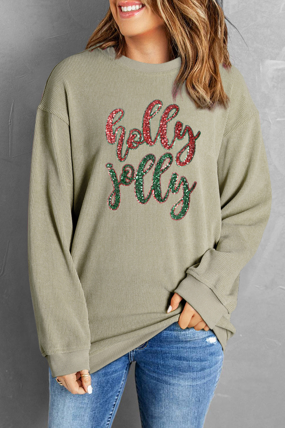 A vibrant green corded sweatshirt featuring a sequined 'holly jolly' graphic, perfect for festive occasions.