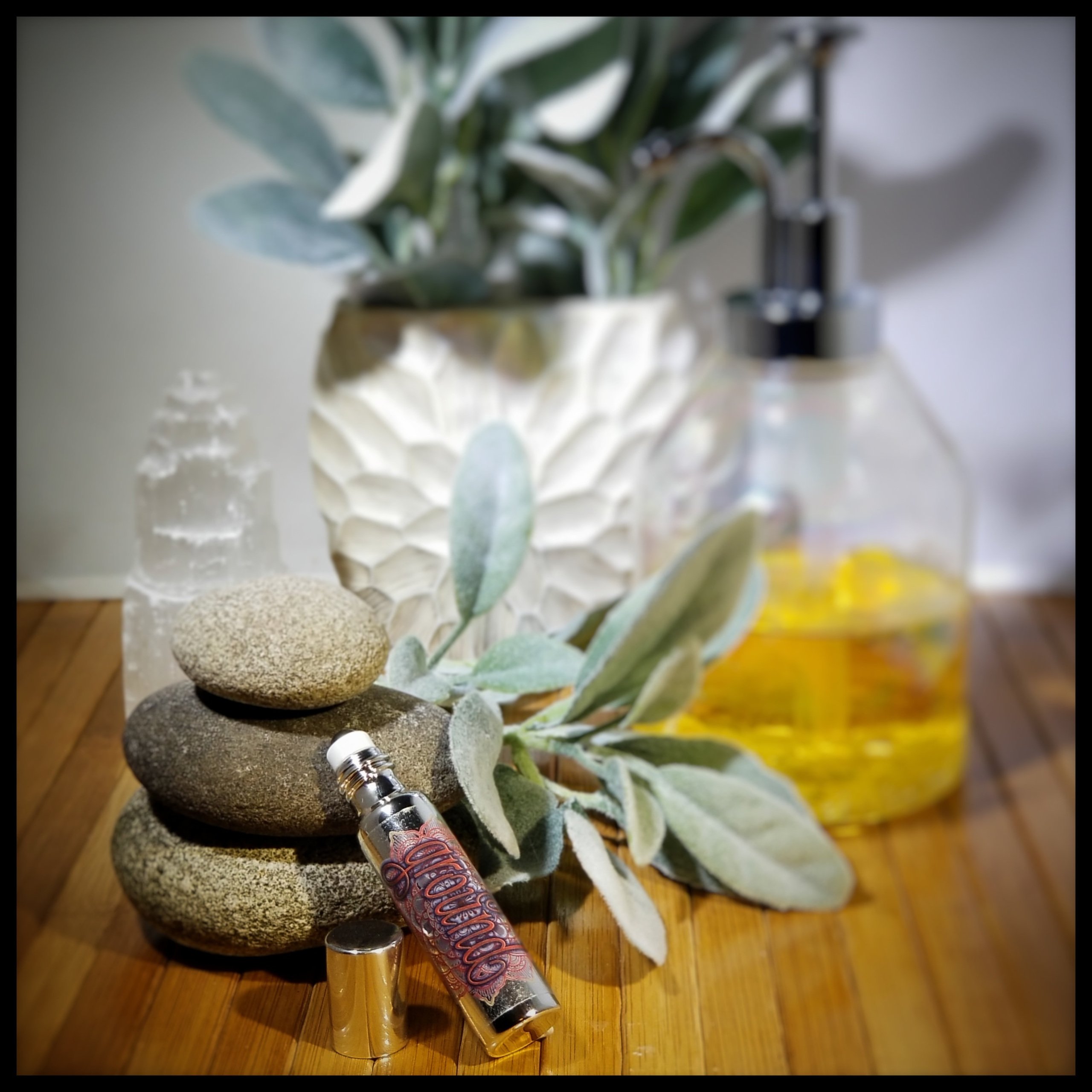 Ground Essential Oil Roll-On in a stylish metallic glass bottle with gemstones inside.