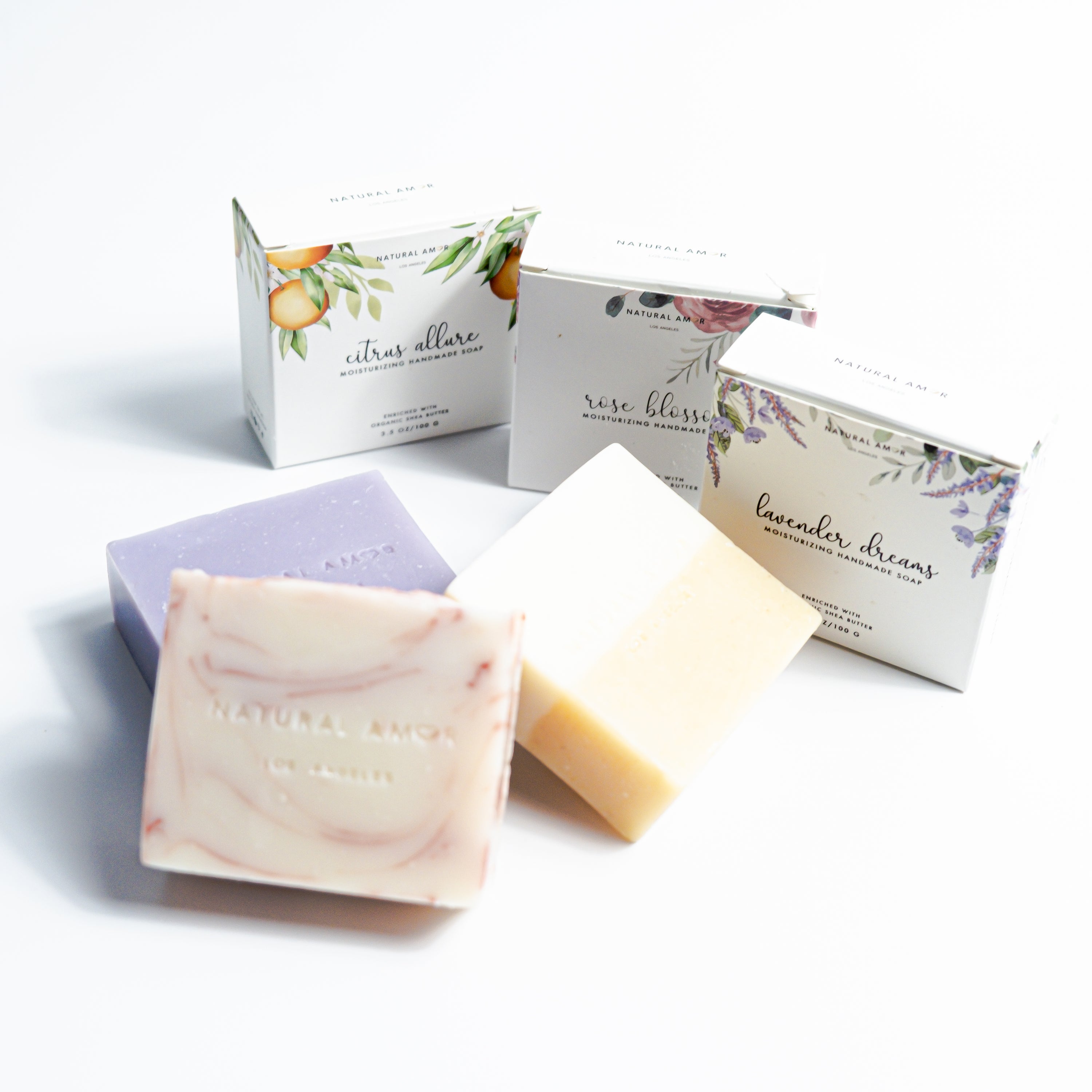 Set of three handmade vegan soaps in lavender, rose, and citrus scents, beautifully packaged.