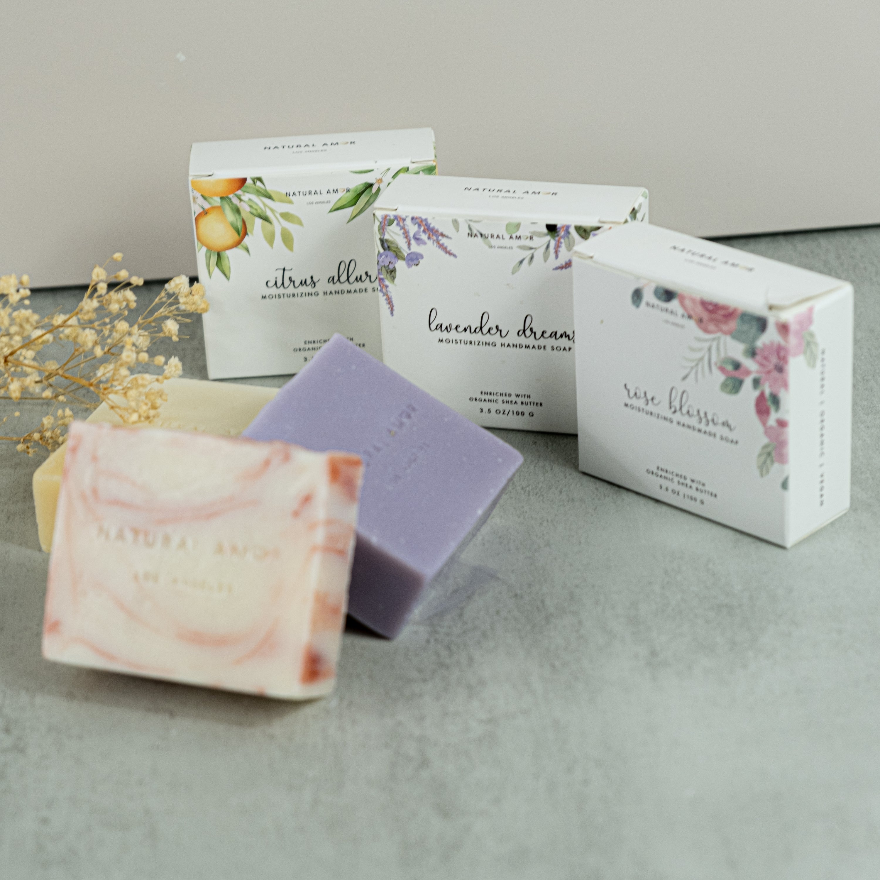 Set of three handmade vegan soaps in lavender, rose, and citrus scents, beautifully packaged.