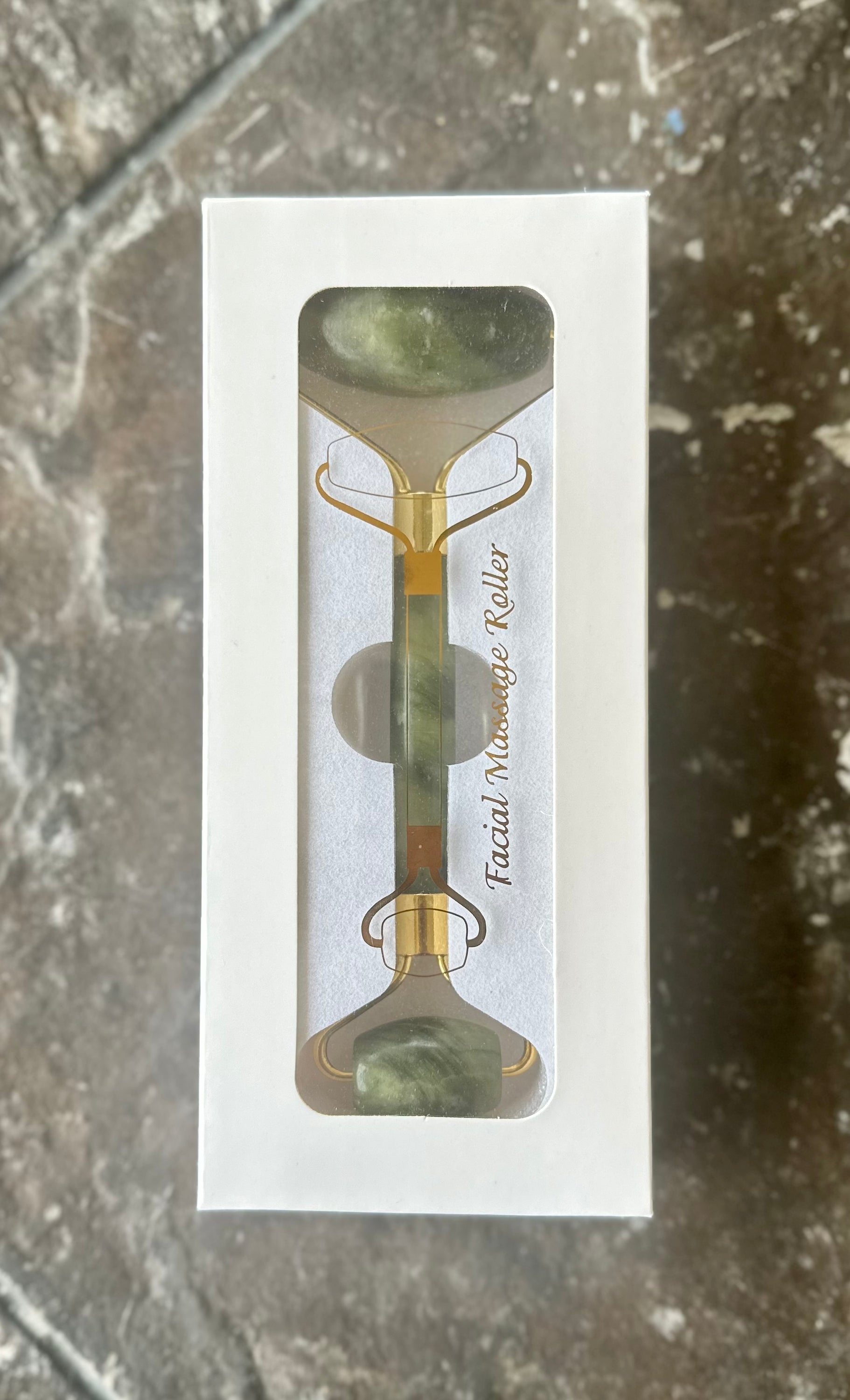 A jade facial roller resting on a soft surface, showcasing its smooth jade stone and elegant design, perfect for facial massages.