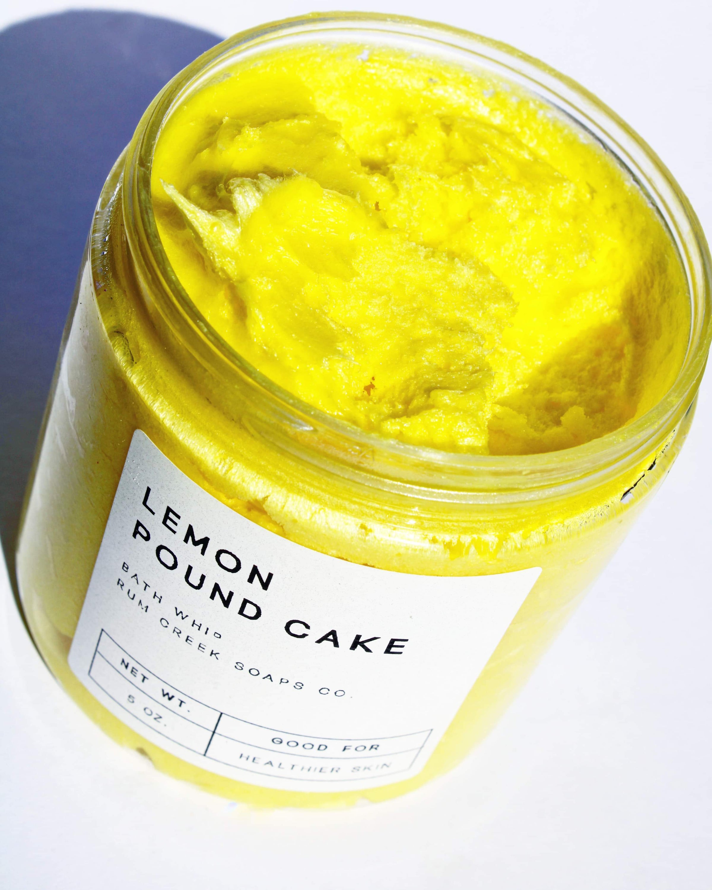 A jar of Lemon Pound Cake Whipped Soap with a fluffy texture, showcasing its vibrant yellow color and sugar crystal topping.