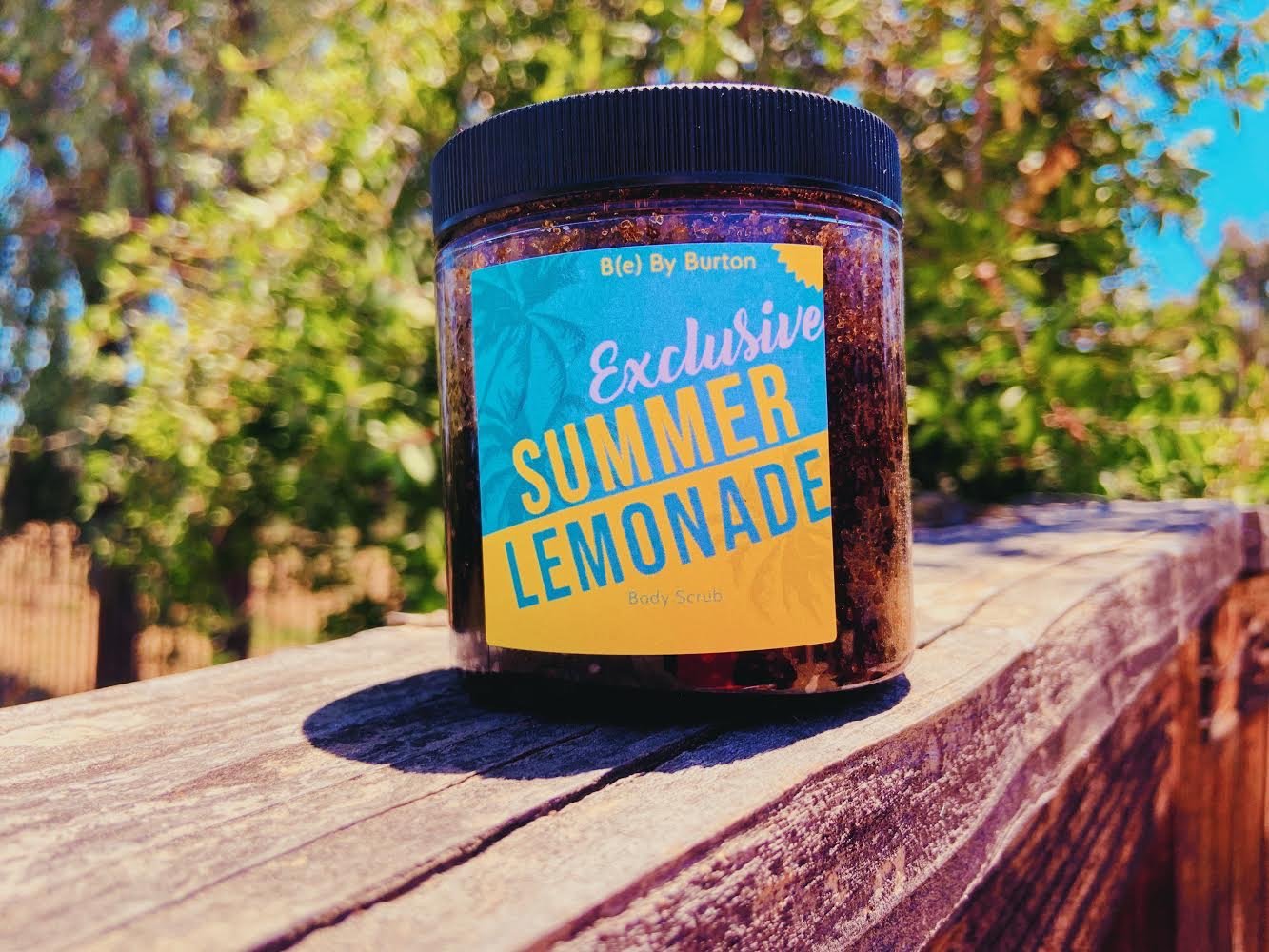 A jar of Lemonade Body Scrub featuring organic ingredients like jojoba oil and lemon essential oil, with a refreshing lemon scent.