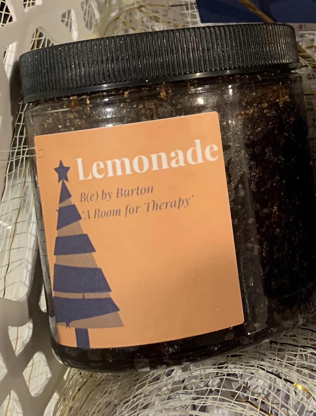 A jar of Lemonade Body Scrub featuring organic ingredients like jojoba oil and lemon essential oil, with a refreshing lemon scent.