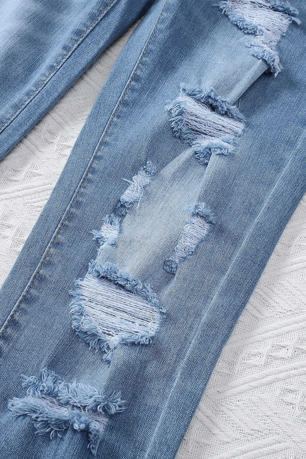 Light blue distressed boyfriend denim pants with a medium rise fit and straight leg silhouette, featuring classic five-pocket styling.