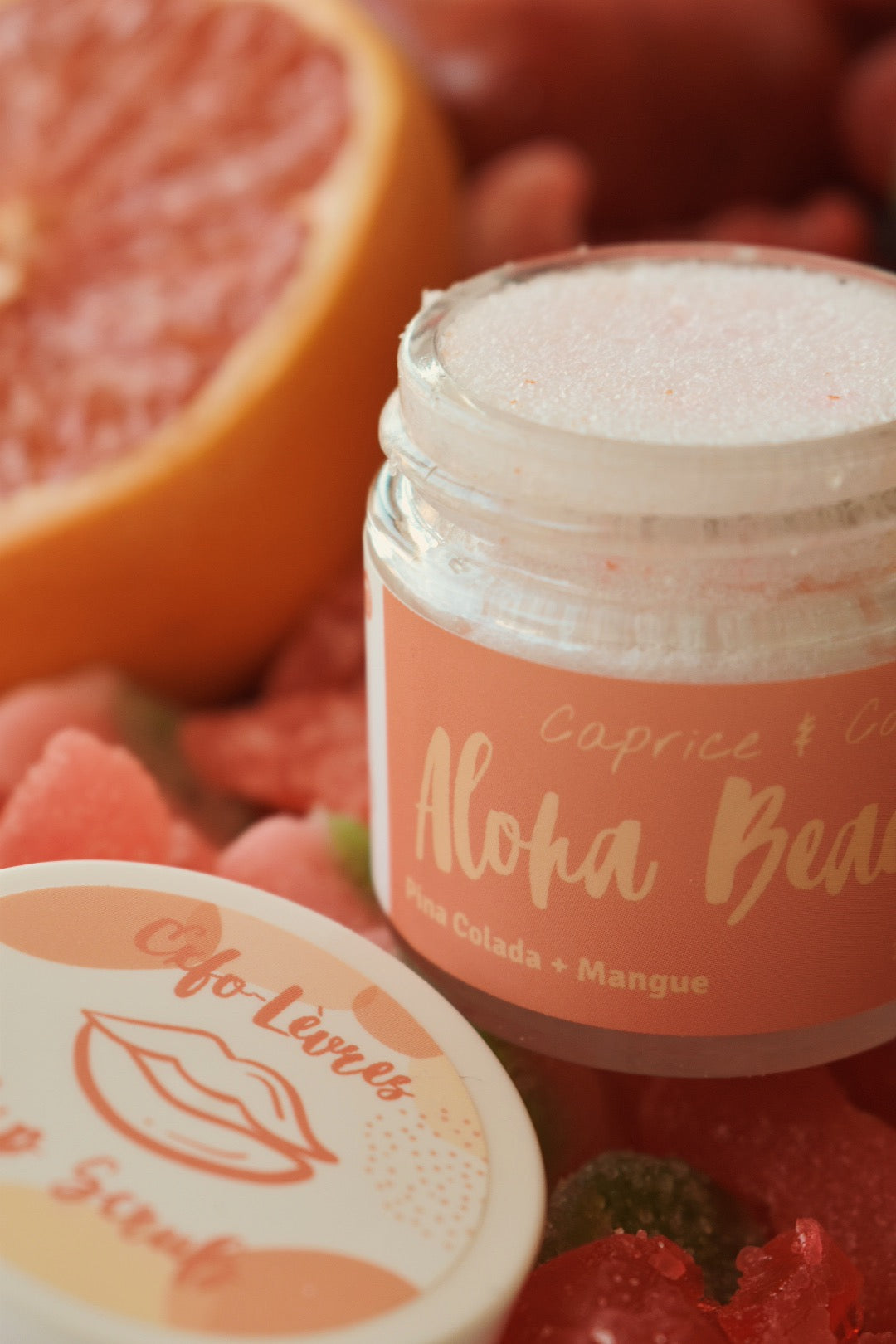 Aloha Beaches Lip Scrub in a jar, featuring tropical Pina Colada and Mango flavors, with a smooth texture and vibrant colors.