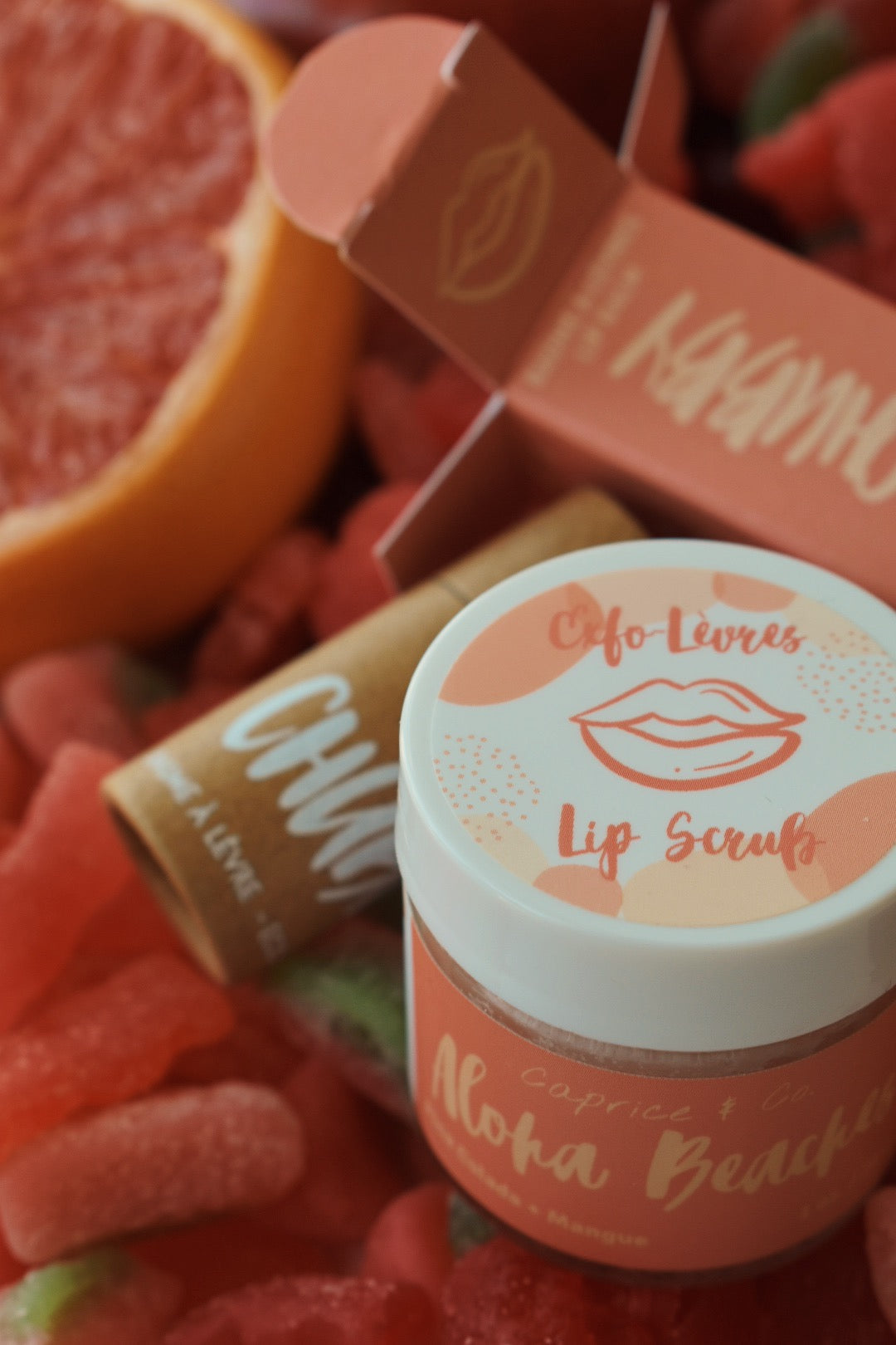 Aloha Beaches Lip Scrub in a jar, featuring tropical Pina Colada and Mango flavors, with a smooth texture and vibrant colors.