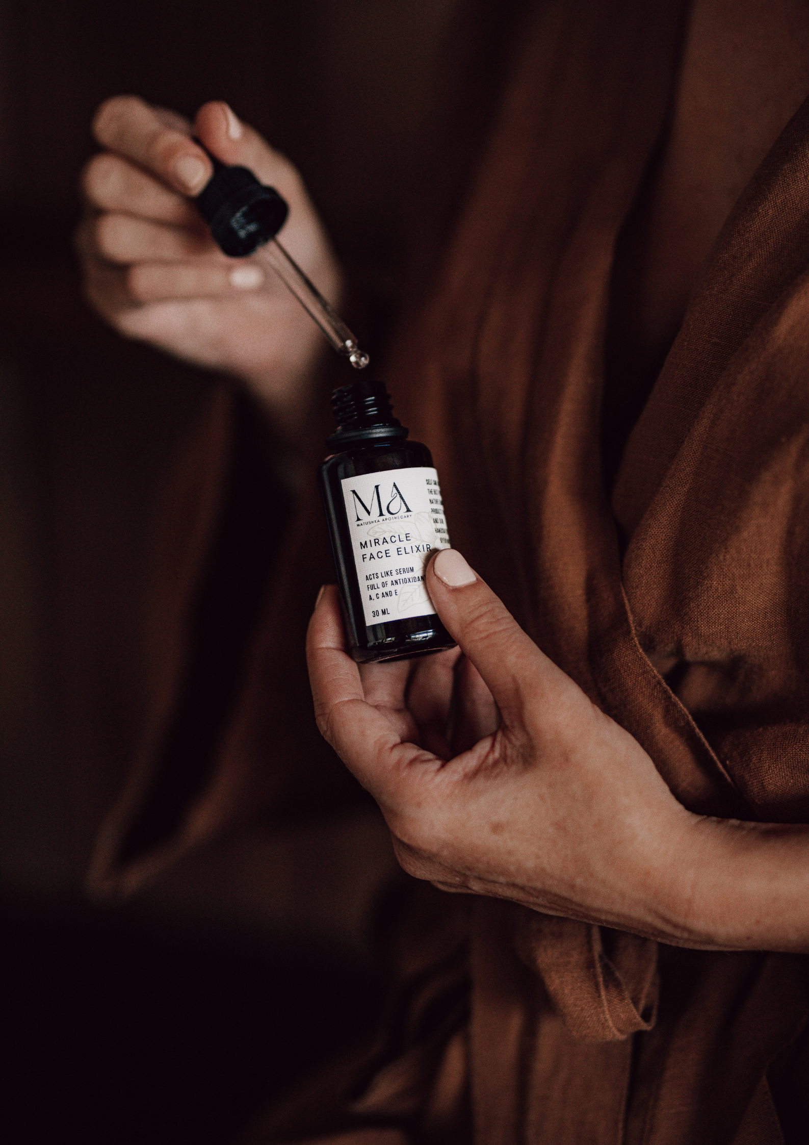 Matushka Miracle Face Elixir in a black miron glass bottle, showcasing its luxurious and organic ingredients.