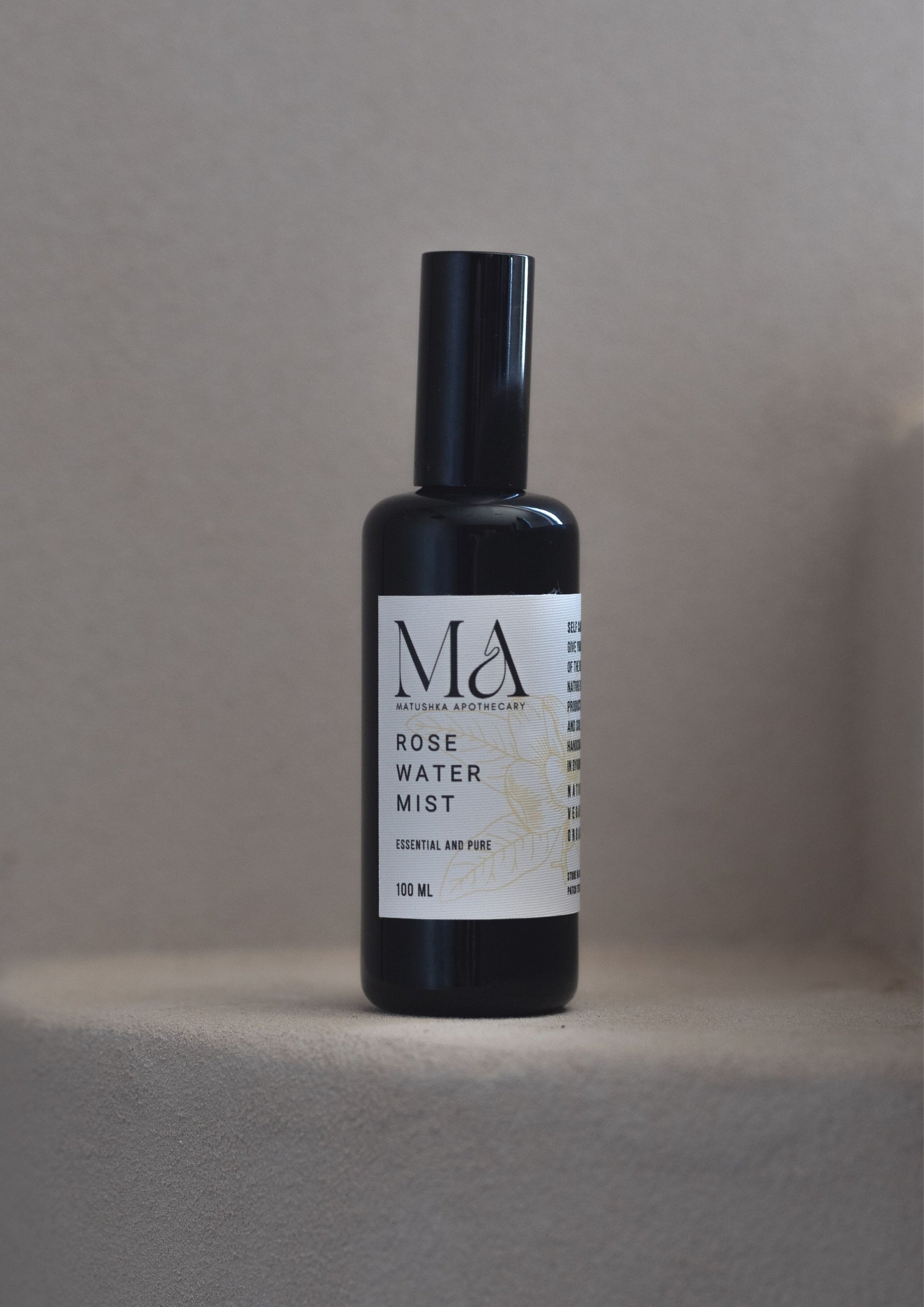 Matushka Premium Organic Rose Water Mist in a black miron glass bottle, showcasing its elegant design and refreshing liquid.