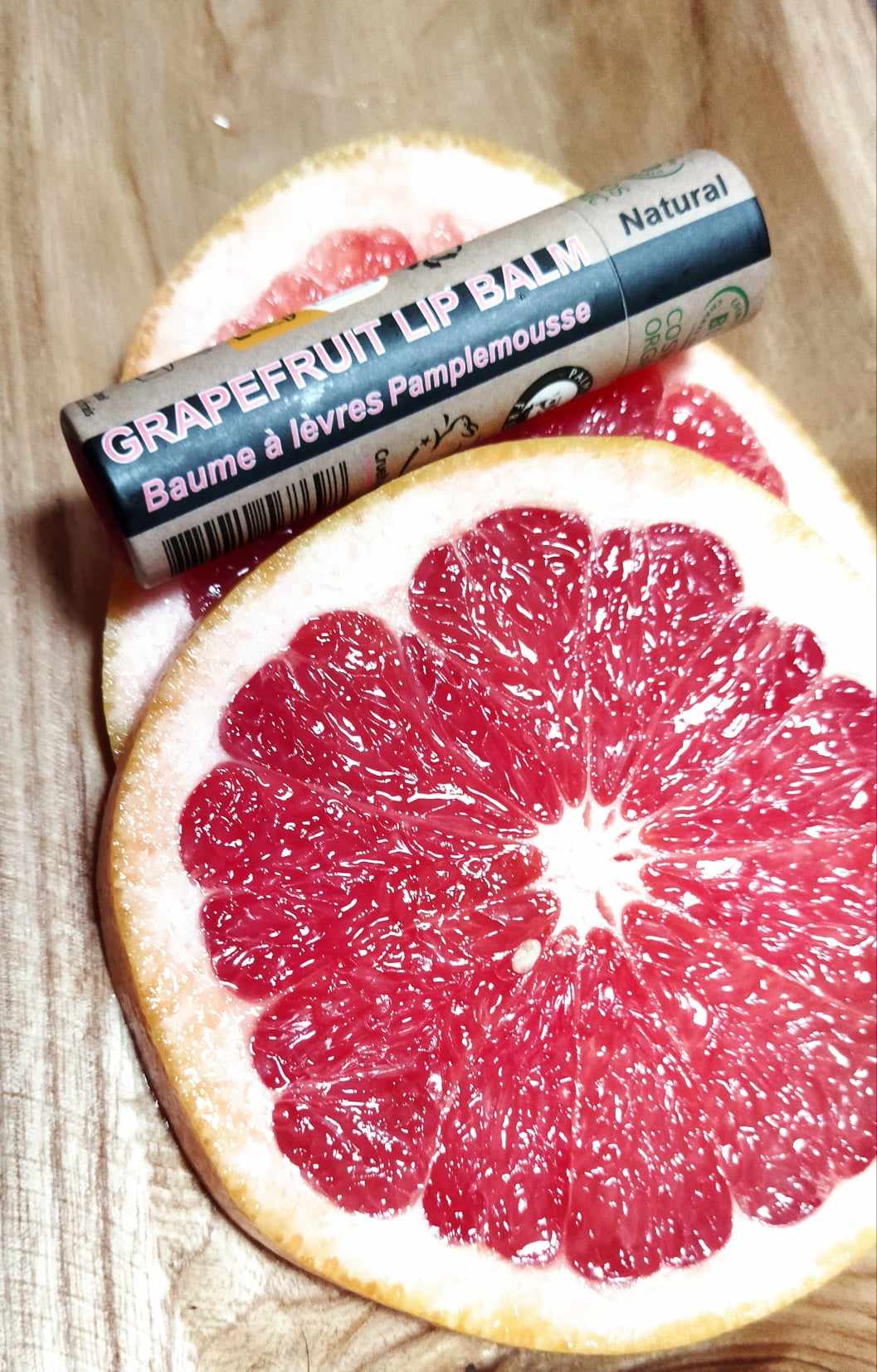 A collection of 30 Organic Pink Grapefruit Lip Balms in 15ml tubes, showcasing their vibrant packaging and natural ingredients.