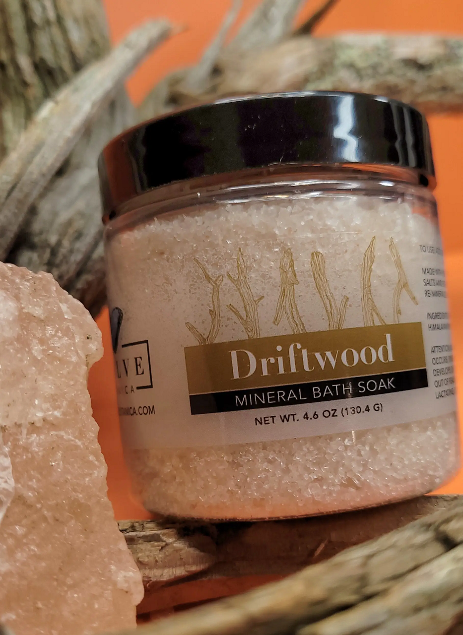 A jar of Mineral Soak - Driftwood bath salt, featuring a blend of Himalayan pink salt, Dead Sea salts, and Pacific solar salts, with a calming driftwood fragrance.