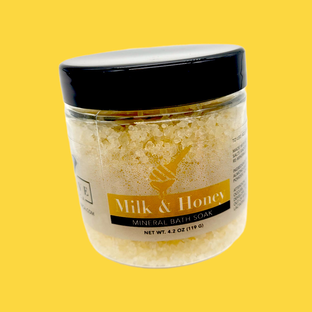 A jar of Mineral Soak - Milk & Honey bath salt featuring a blend of natural ingredients, including Dead Sea salts and honey powder.