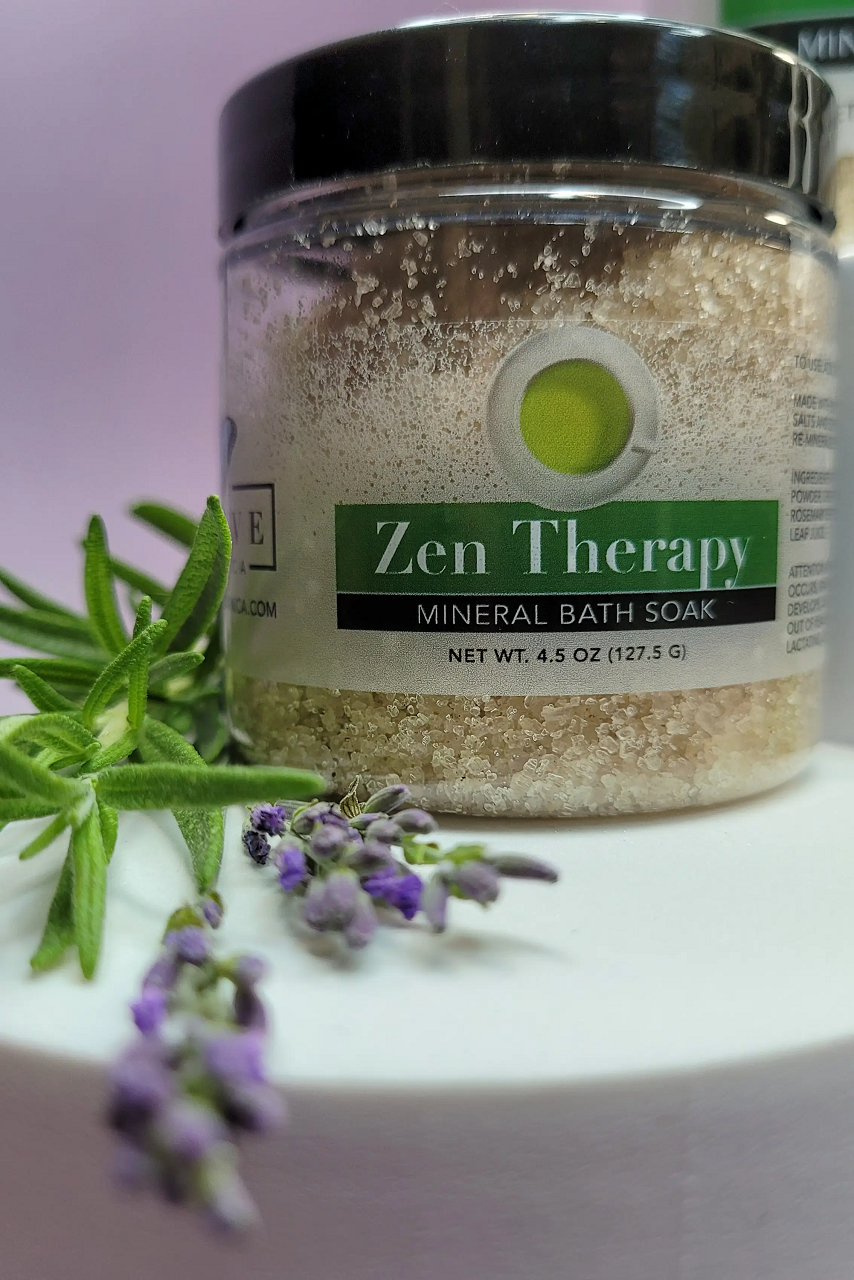 A jar of Mineral Soak - Zen bath salt featuring a blend of dead sea salts, lavender, and rosemary essential oils, surrounded by natural elements.