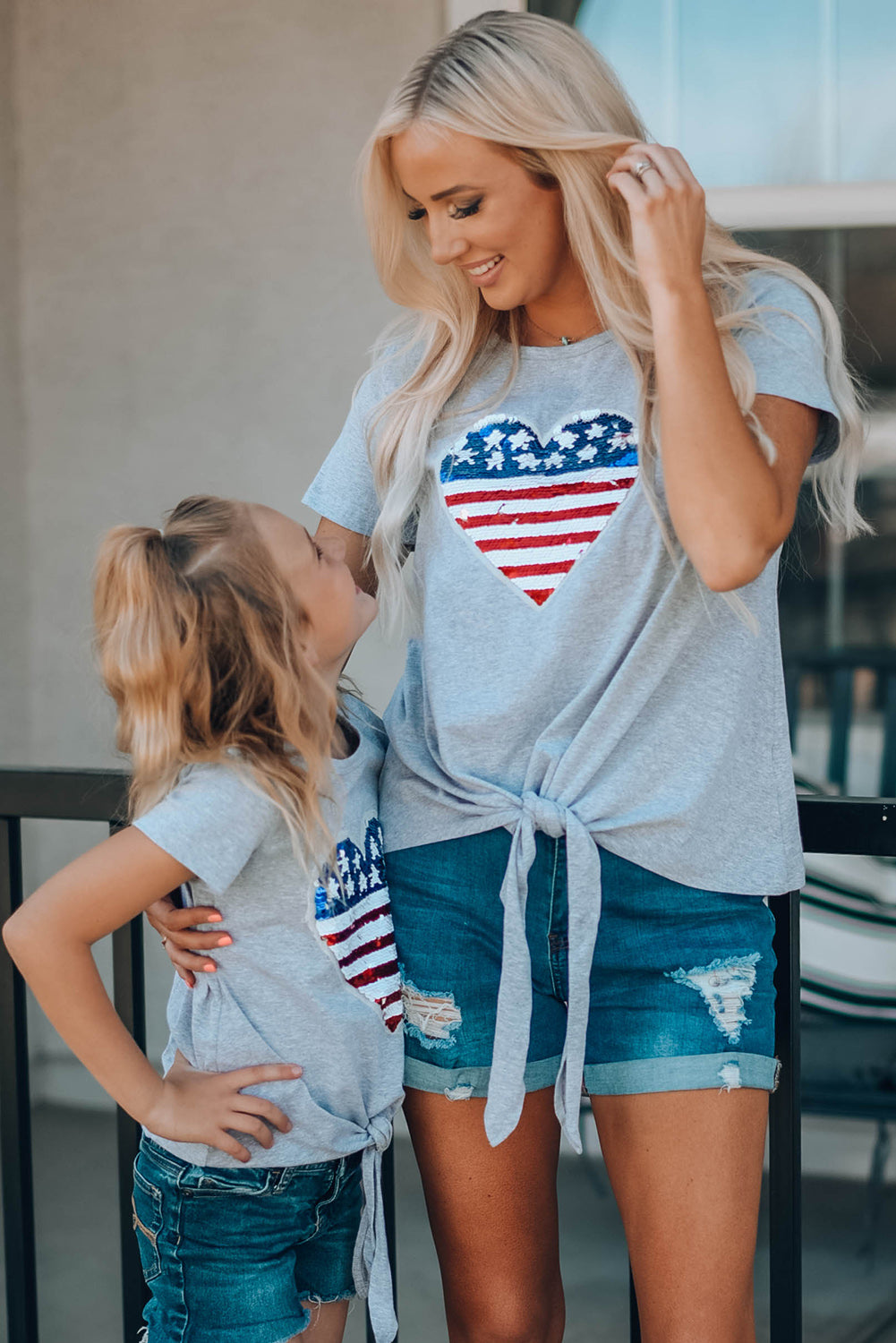 Mommy Patriotic Flag Sequin Heart Applique Knot Top featuring a heart-shaped flag design, soft gray fabric, and stylish knot hem.