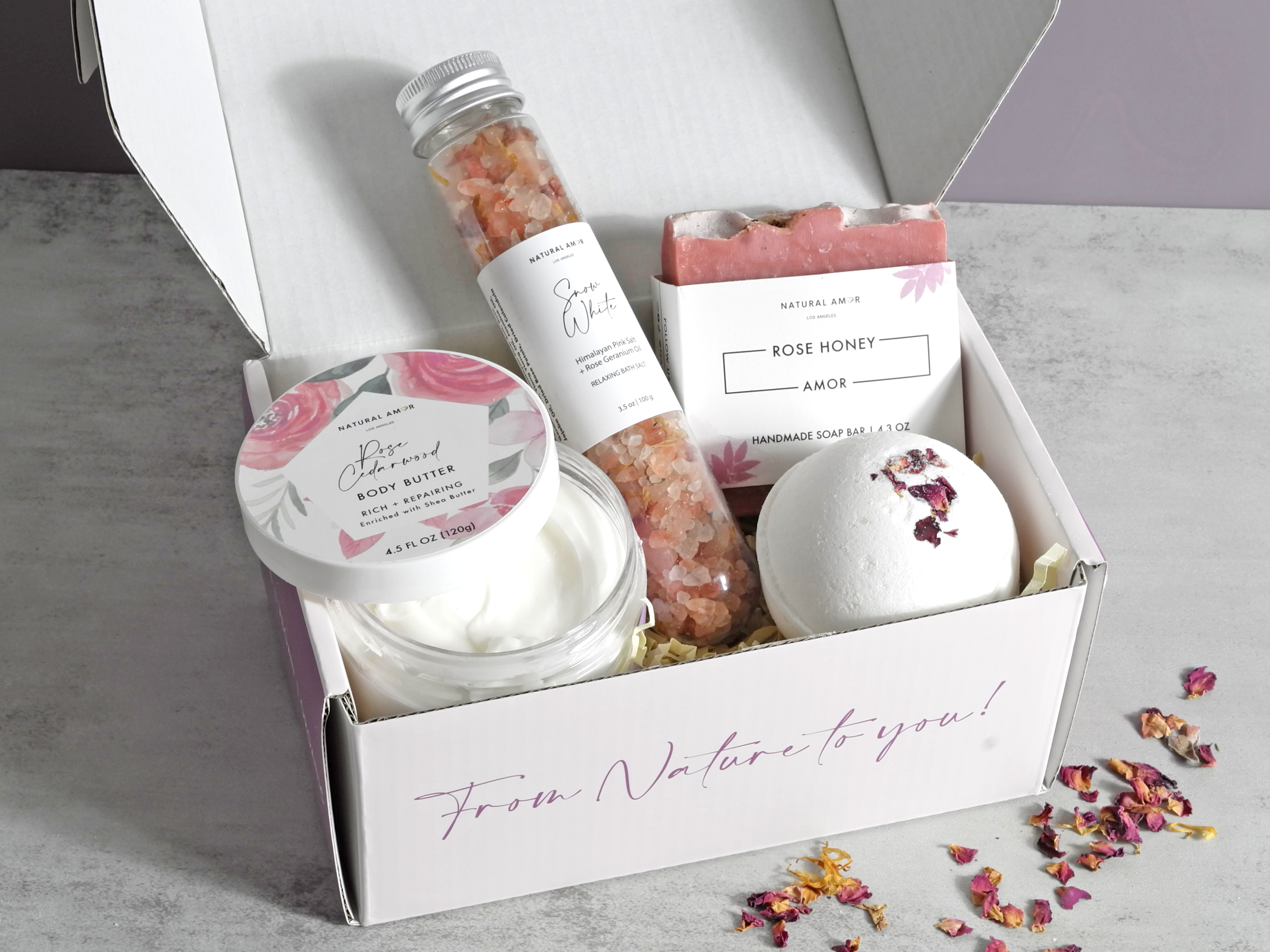 Mother's Embrace gift box featuring vegan skincare products including soap, bath salt, body butter, and bath bomb in rose and lavender scents.