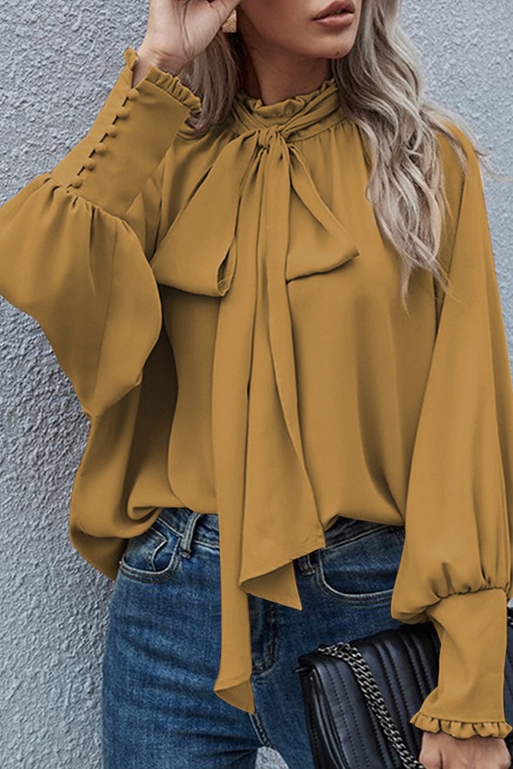 Mustard blouse featuring frilled knotted mock neck and bishop sleeves, showcasing a chic and elegant design.