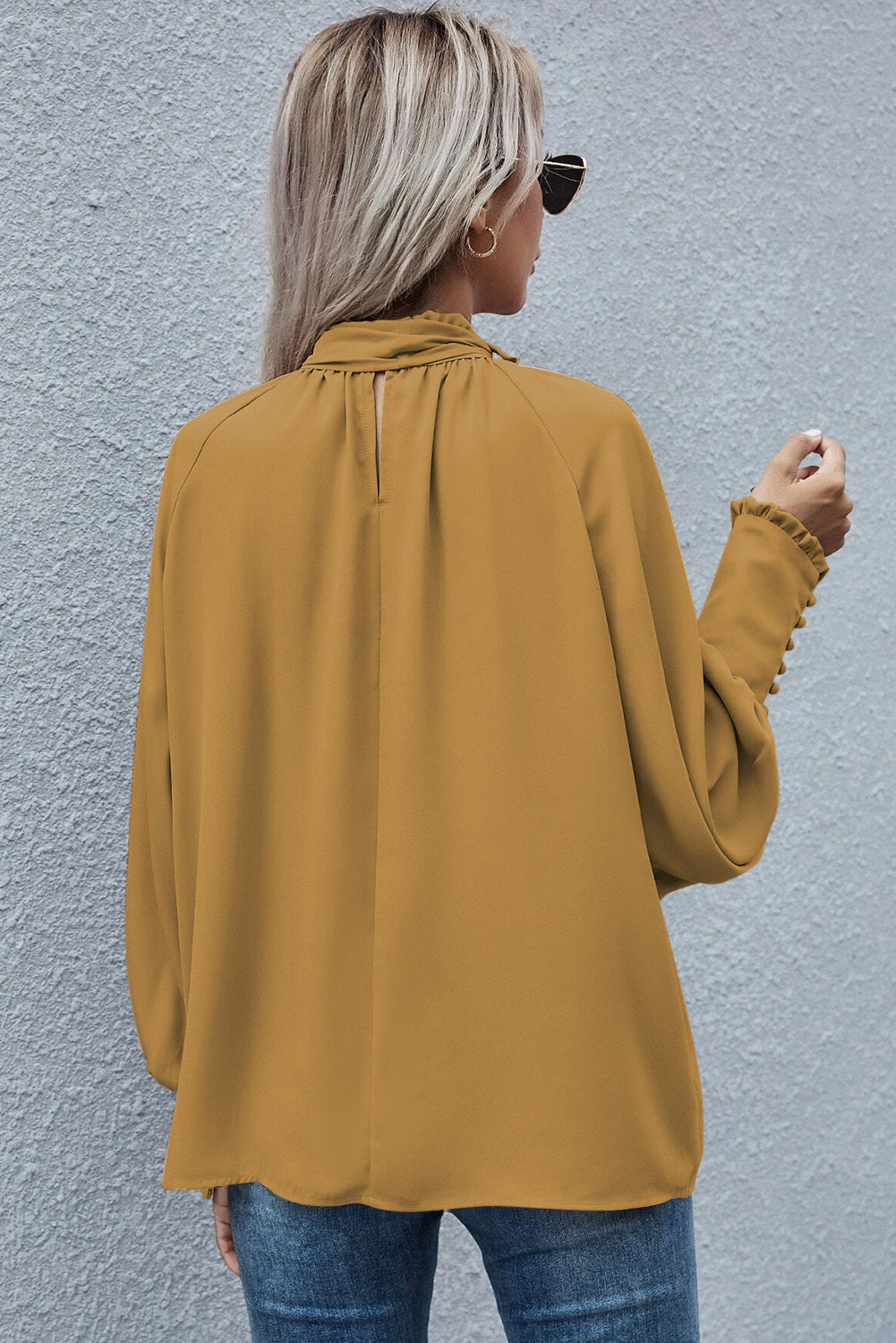 Mustard blouse featuring frilled knotted mock neck and bishop sleeves, showcasing a chic and elegant design.