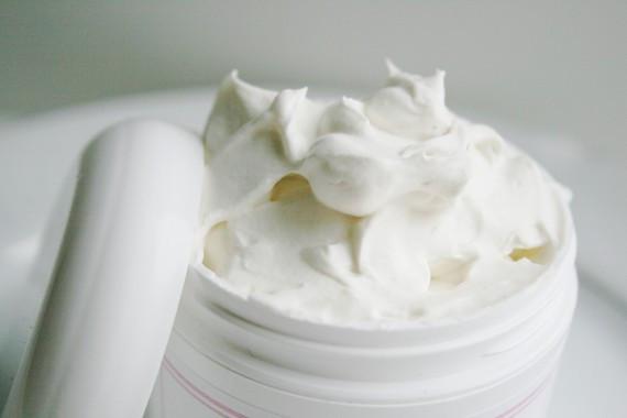 A jar of Natural Shea Whipped Body Butter with a creamy texture, surrounded by natural ingredients like cocoa butter and jojoba oil, showcasing its moisturizing properties.