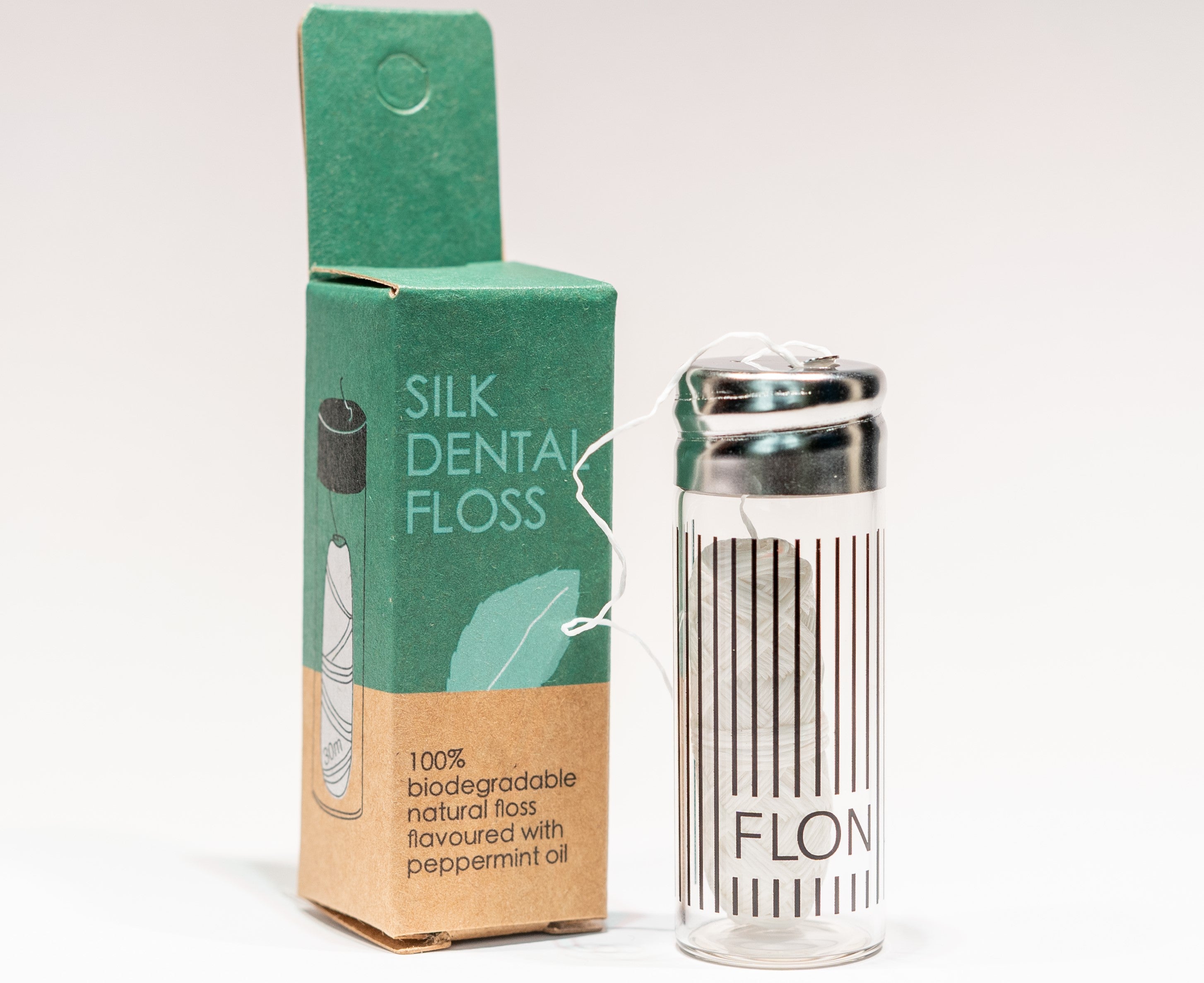 Natural Silk Dental Floss in a reusable glass dispenser with a metal cap, featuring a strong silk thread coated in Candelilla wax and peppermint flavor.