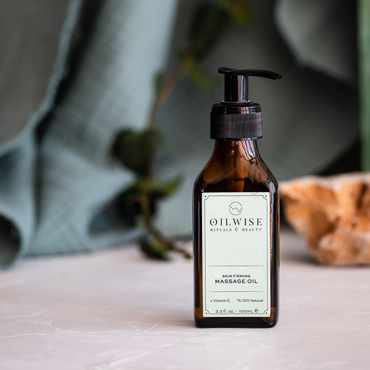 Oilwise Hautstraffendes Massageöl in einer eleganten Flasche, umgeben von natürlichen Zutaten wie Oliven, Orangen und Lavendel.