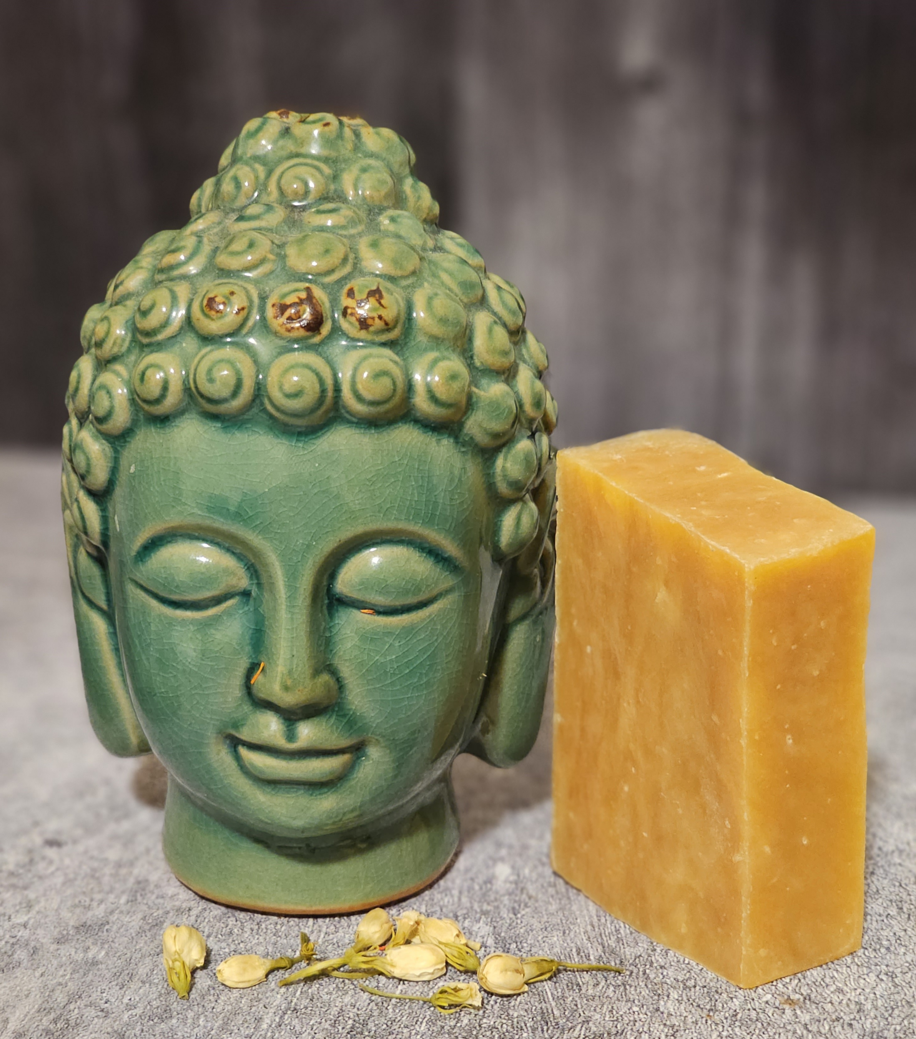 A bar of Orange Lemongrass Soap showcasing its vibrant orange color and textured surface, surrounded by fresh lemongrass and orange slices.