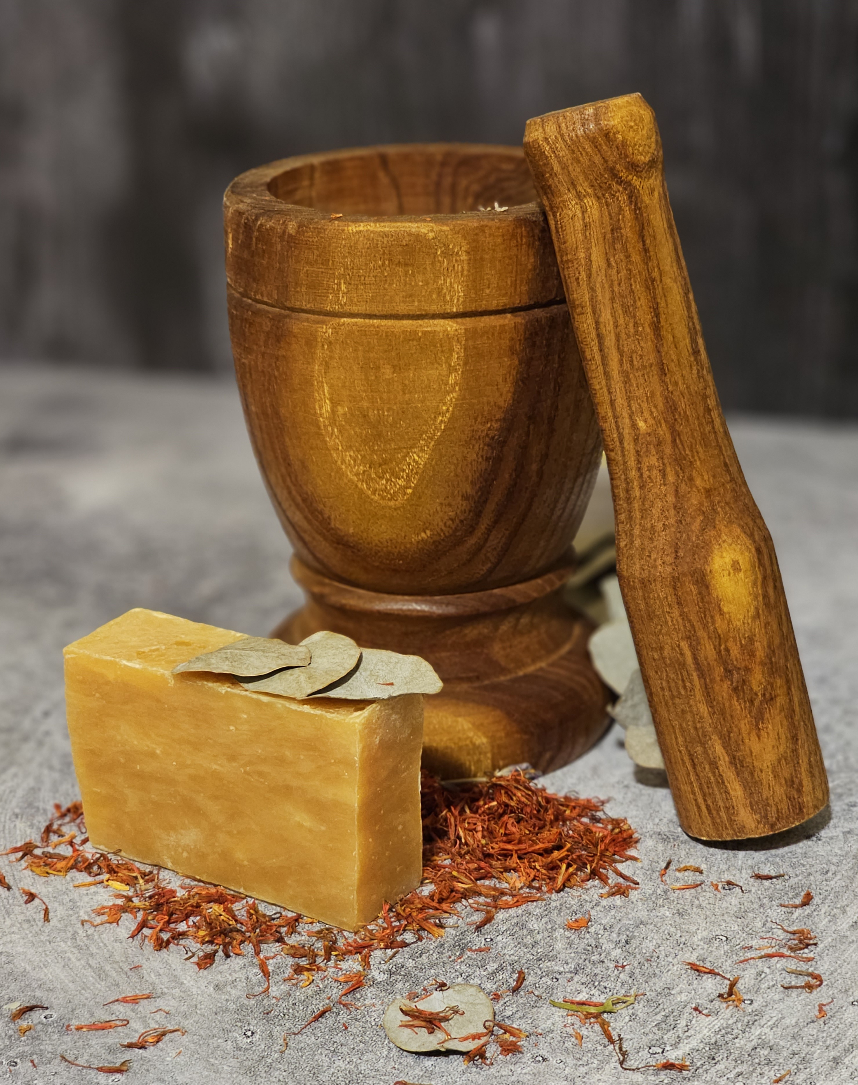 A bar of Orange Lemongrass Soap showcasing its vibrant orange color and textured surface, surrounded by fresh lemongrass and orange slices.