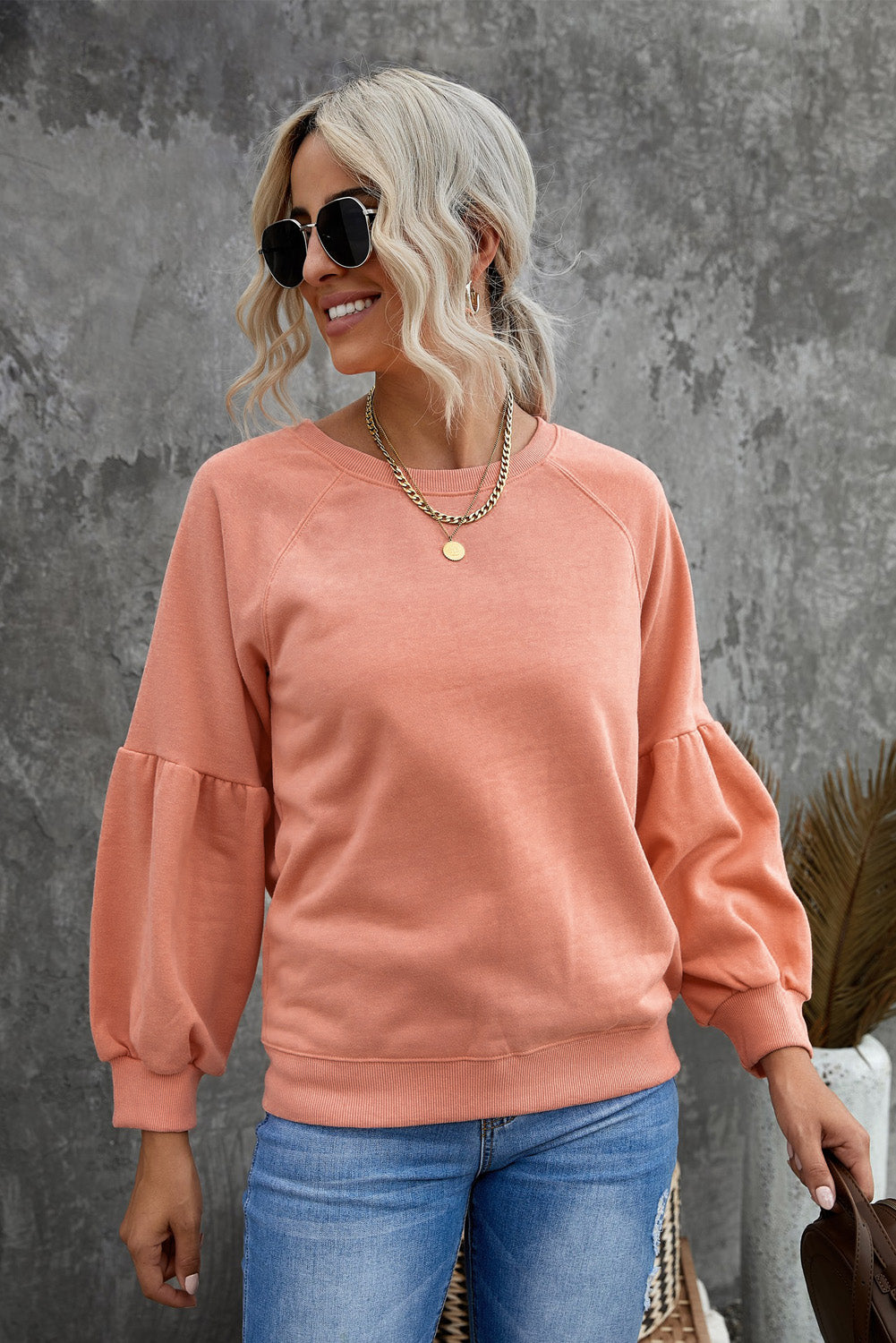 Orange pullover sweatshirt with patchwork raglan sleeves, showcasing a trendy and stylish design suitable for casual wear.