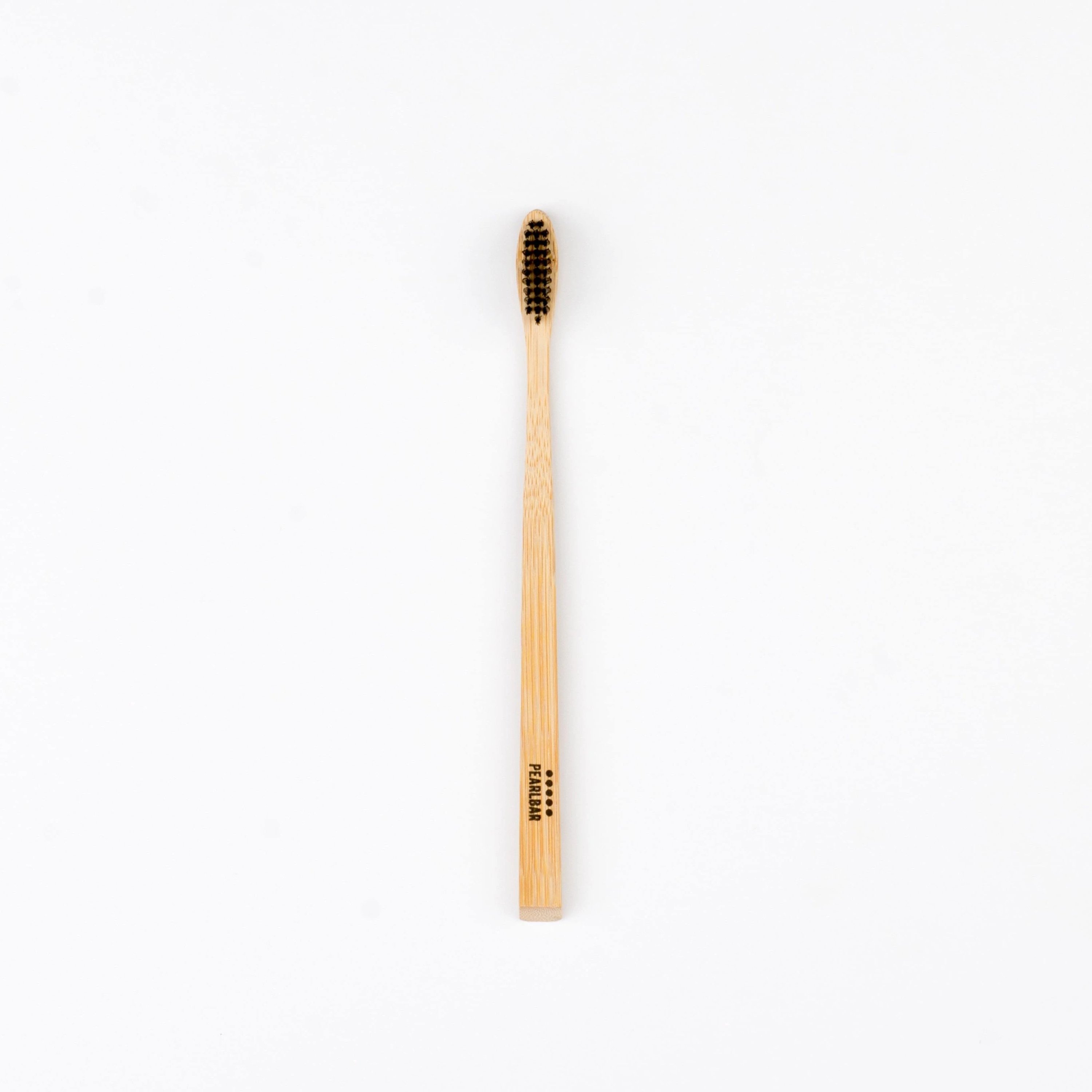 PearlBar Bamboo & Charcoal Toothbrush with a bamboo handle and charcoal-infused bristles, showcasing its eco-friendly design.