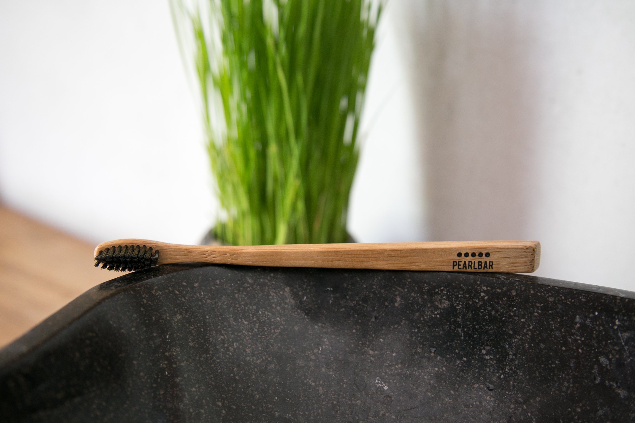 PearlBar Bamboo & Charcoal Toothbrush with a bamboo handle and charcoal-infused bristles, showcasing its eco-friendly design.