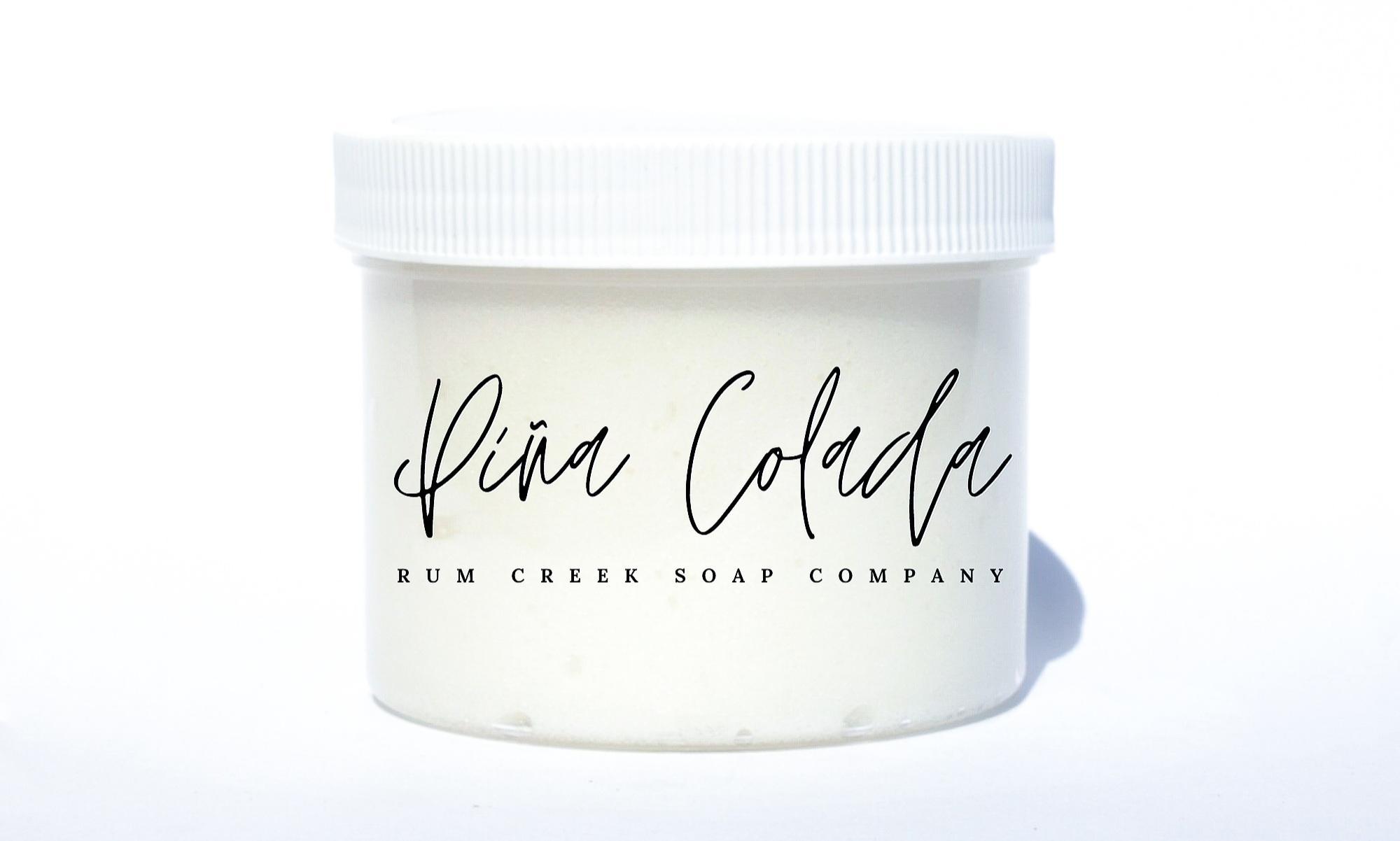 A jar of Pina Colada Sugar Scrub with tropical ingredients, showcasing its creamy texture and vibrant color.