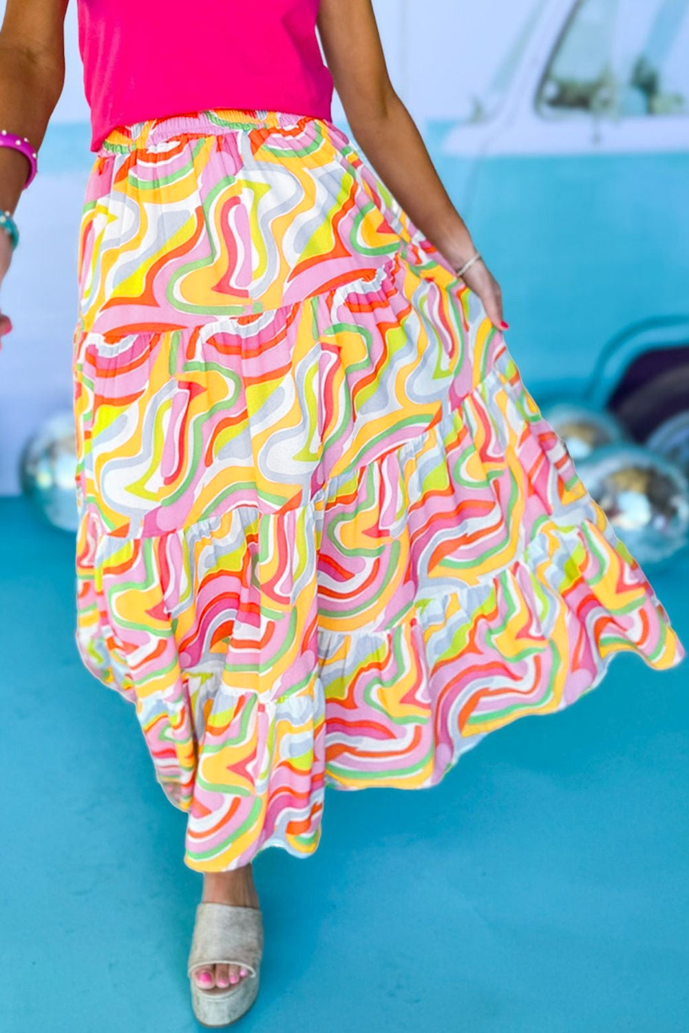 A flowy maxi skirt featuring a vibrant pink abstract print, showcasing a tiered design that adds elegance and movement.