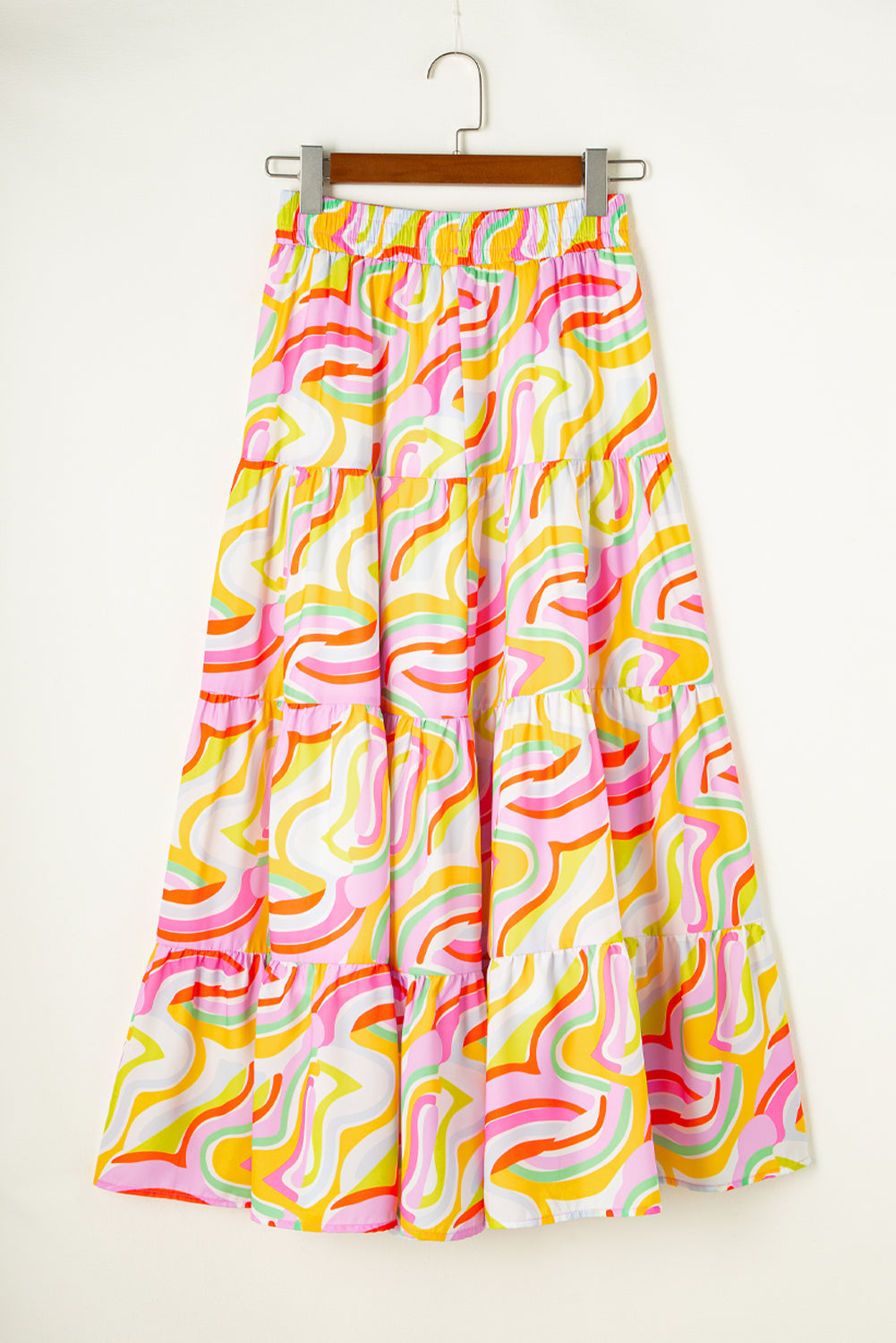 A flowy maxi skirt featuring a vibrant pink abstract print, showcasing a tiered design that adds elegance and movement.