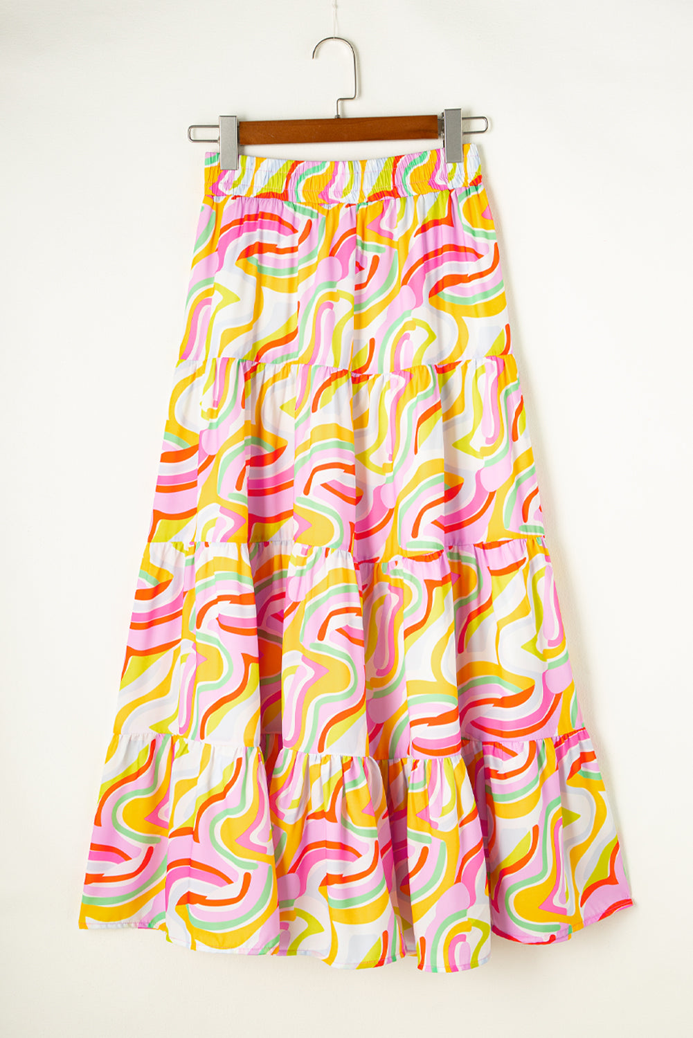 A flowy maxi skirt featuring a vibrant pink abstract print, showcasing a tiered design that adds elegance and movement.