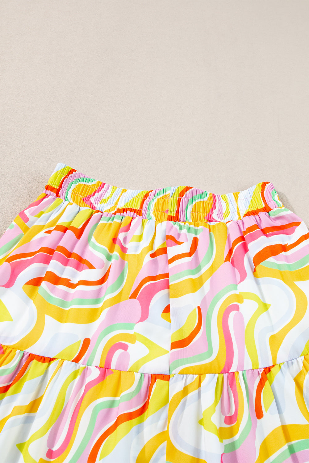 A flowy maxi skirt featuring a vibrant pink abstract print, showcasing a tiered design that adds elegance and movement.