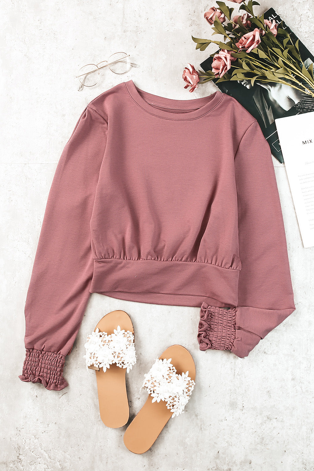 A stylish pink long sleeve crop top with banded hem and smocking cuffs, perfect for casual wear.