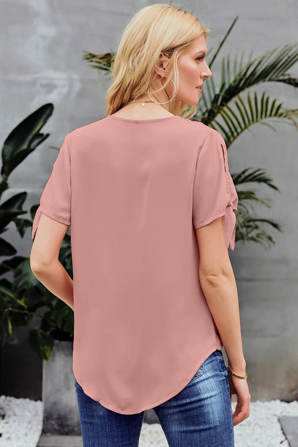 A stylish pink blouse with a v neckline, drape silhouette, rolled hemline, and tie sleeves, perfect for both office and casual wear.