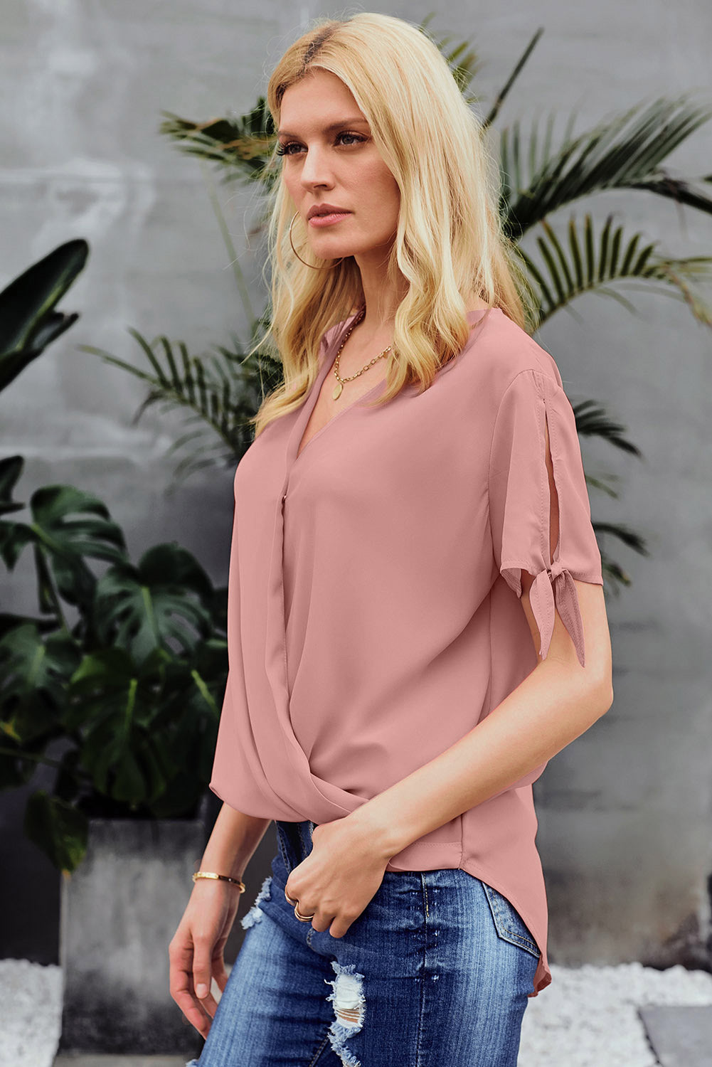 A stylish pink blouse with a v neckline, drape silhouette, rolled hemline, and tie sleeves, perfect for both office and casual wear.