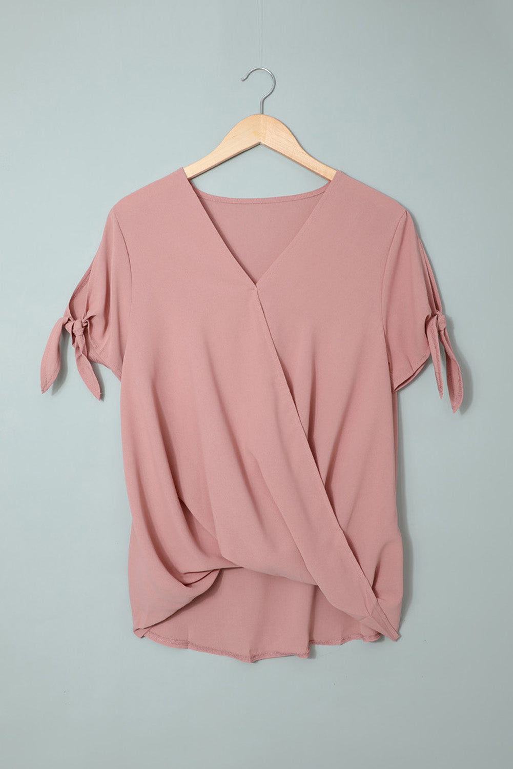 A stylish pink blouse with a v neckline, drape silhouette, rolled hemline, and tie sleeves, perfect for both office and casual wear.