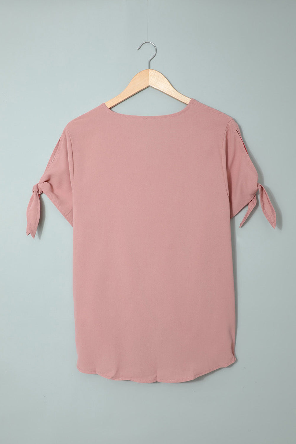 A stylish pink blouse with a v neckline, drape silhouette, rolled hemline, and tie sleeves, perfect for both office and casual wear.