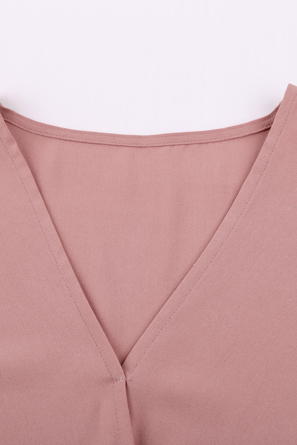 A stylish pink blouse with a v neckline, drape silhouette, rolled hemline, and tie sleeves, perfect for both office and casual wear.