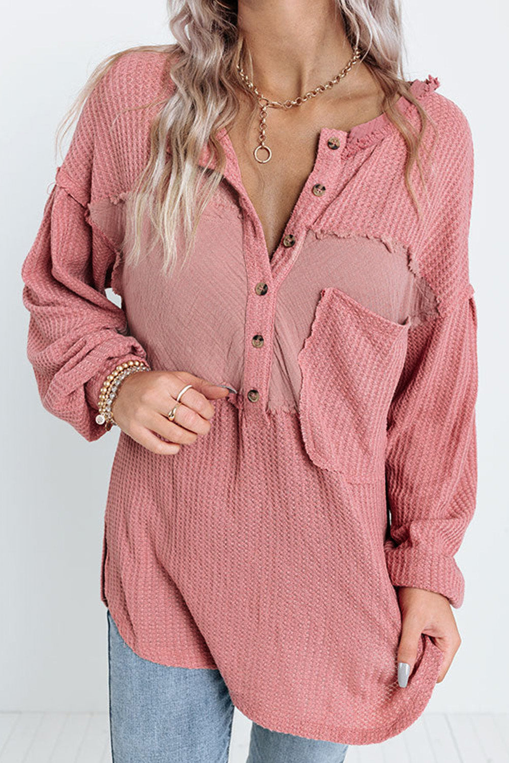 A stylish pink frayed patchwork waffle knit top featuring a buttoned neckline, drop shoulders, and a patch pocket, perfect for casual wear.