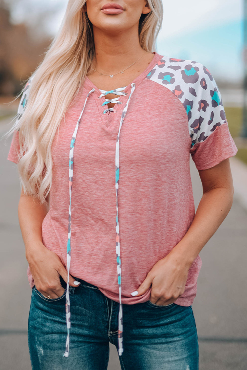 A stylish pink t-shirt featuring lace-up detail and leopard print raglan sleeves, perfect for casual wear.