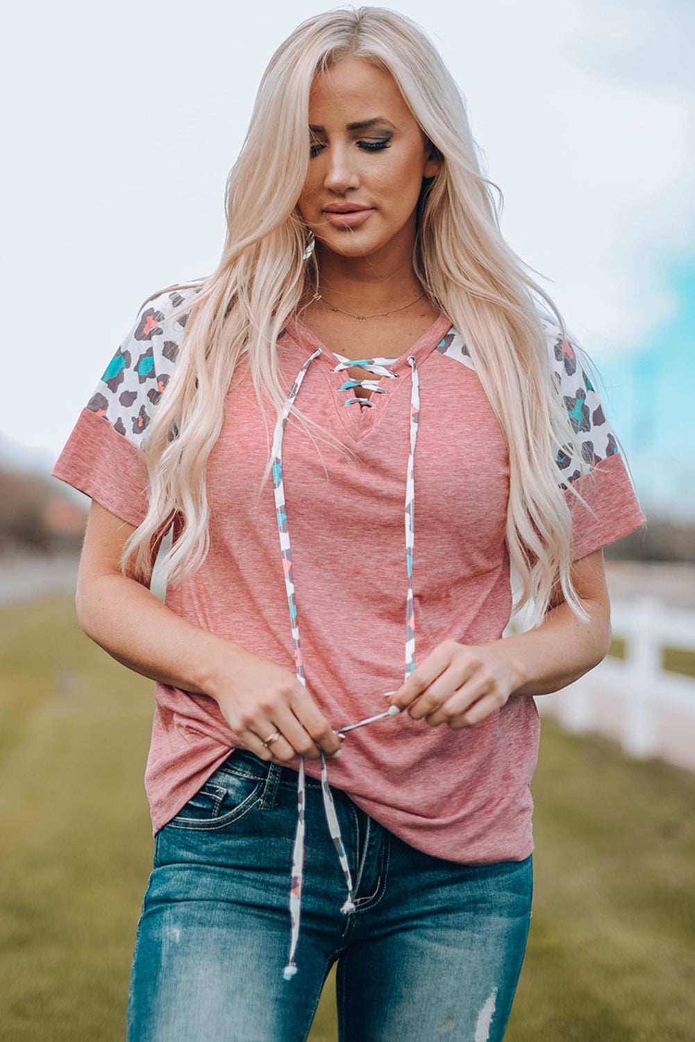 A stylish pink t-shirt featuring lace-up detail and leopard print raglan sleeves, perfect for casual wear.