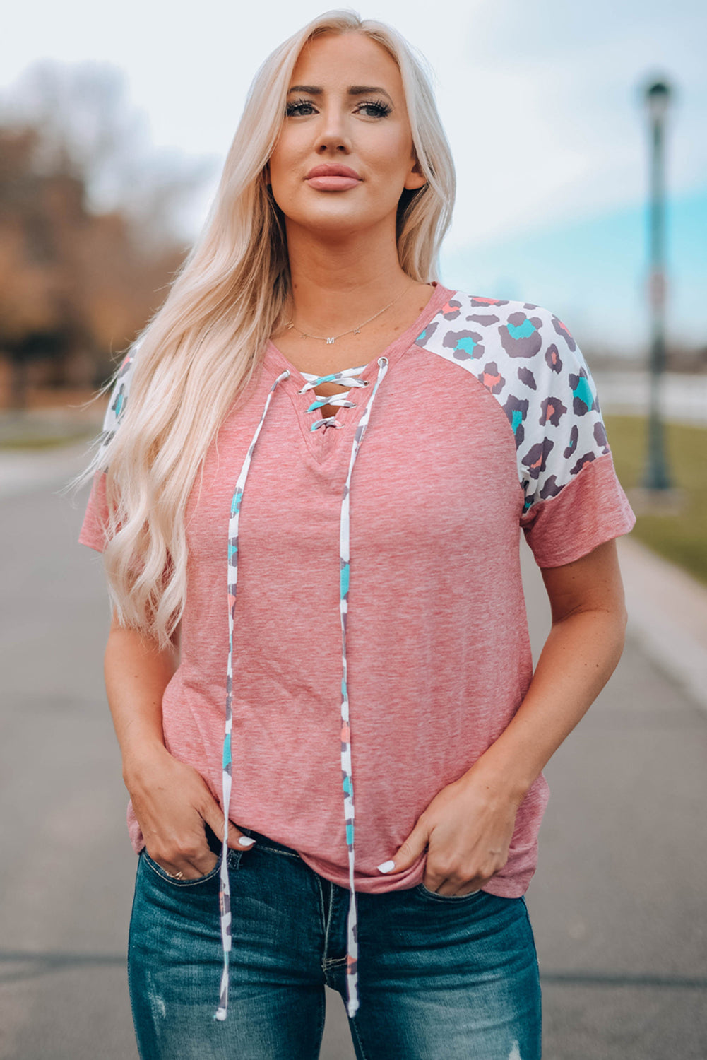 A stylish pink t-shirt featuring lace-up detail and leopard print raglan sleeves, perfect for casual wear.