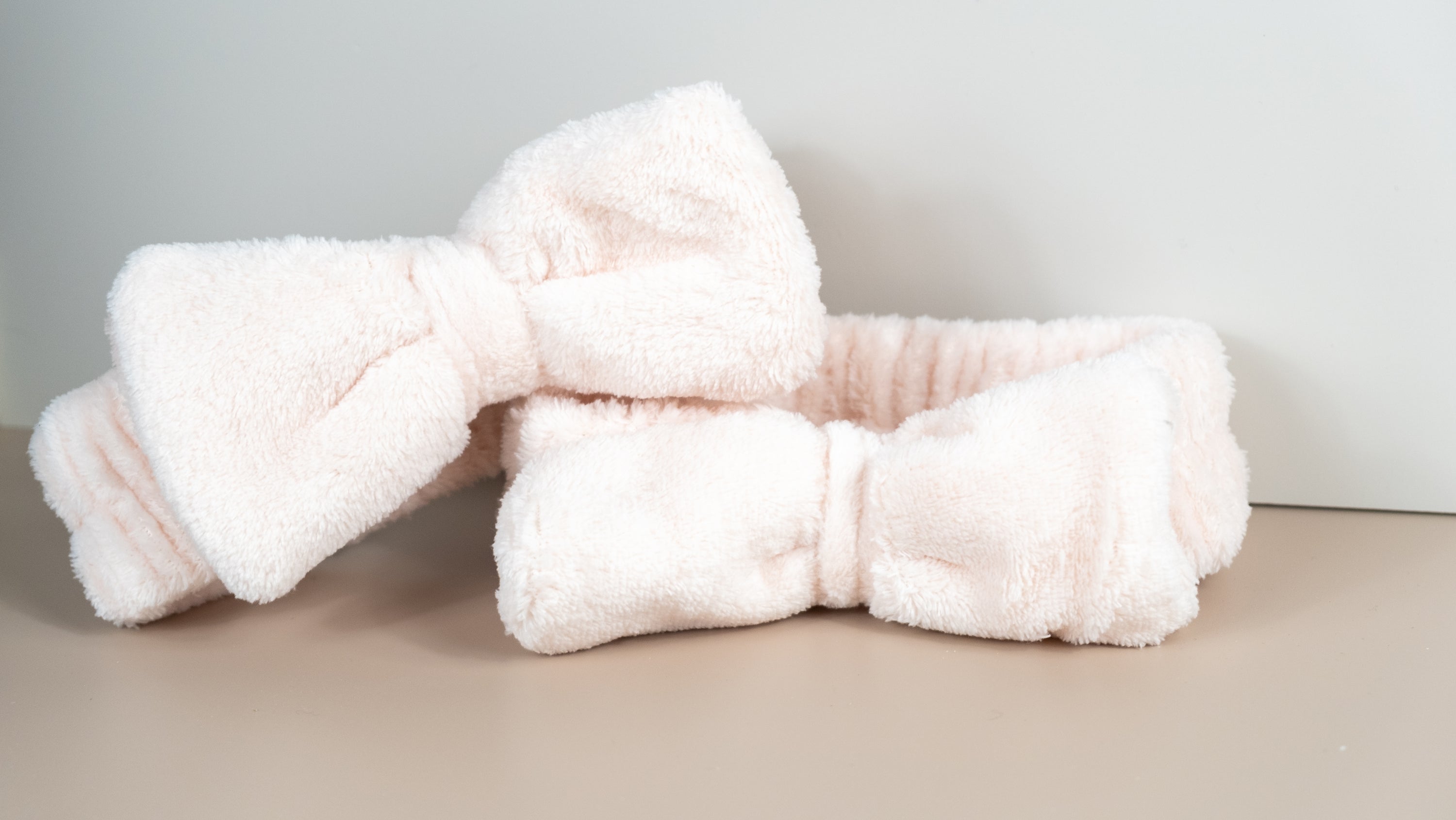 A pink soft fleece headband with a cute bow, perfect for spa days and yoga sessions, designed to keep hair away from the face.