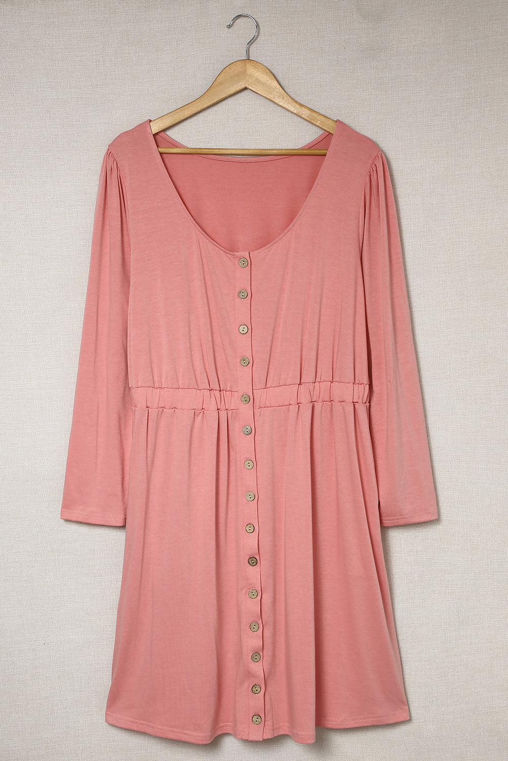 A stylish pink solid button front plus size long sleeve dress displayed on a mannequin, featuring a scoop neck and side pockets.