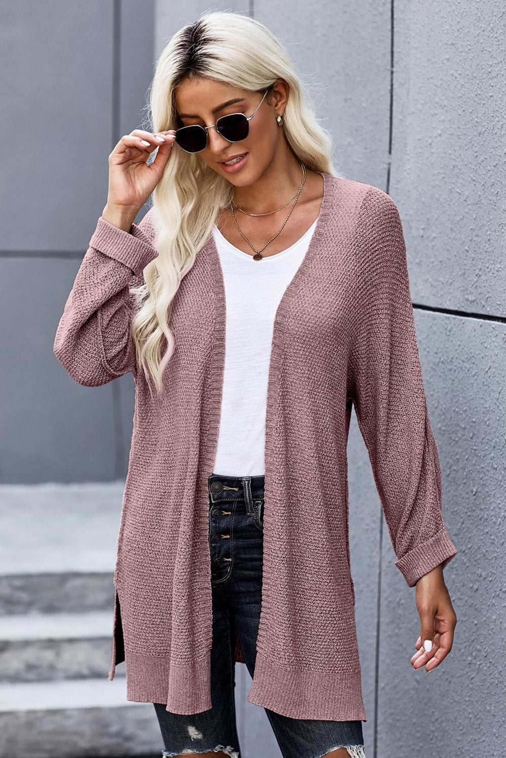 A stylish pink solid color loose fit open front knitted cardigan with cuffed long sleeves, perfect for layering over outfits.