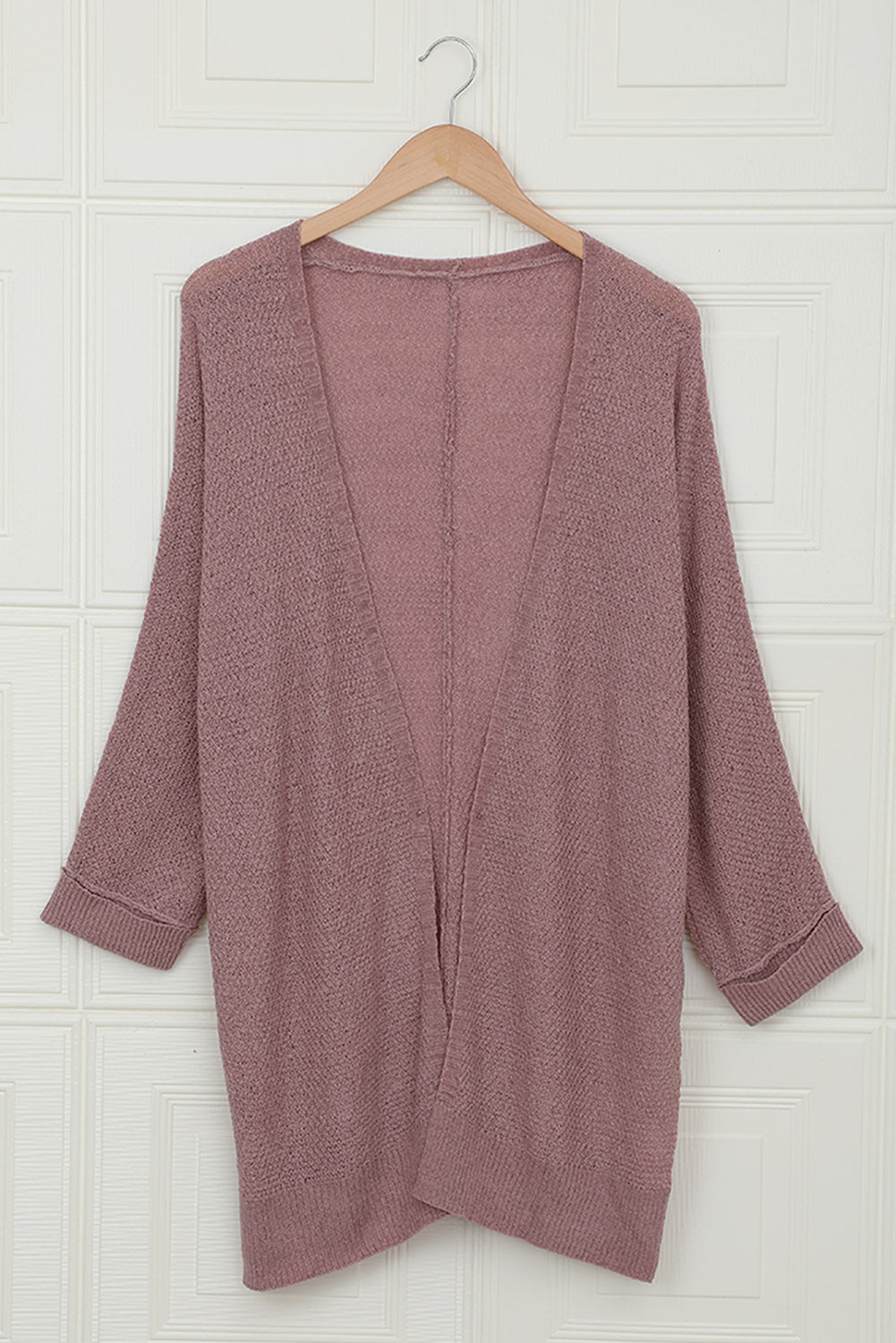 A stylish pink solid color loose fit open front knitted cardigan with cuffed long sleeves, perfect for layering over outfits.