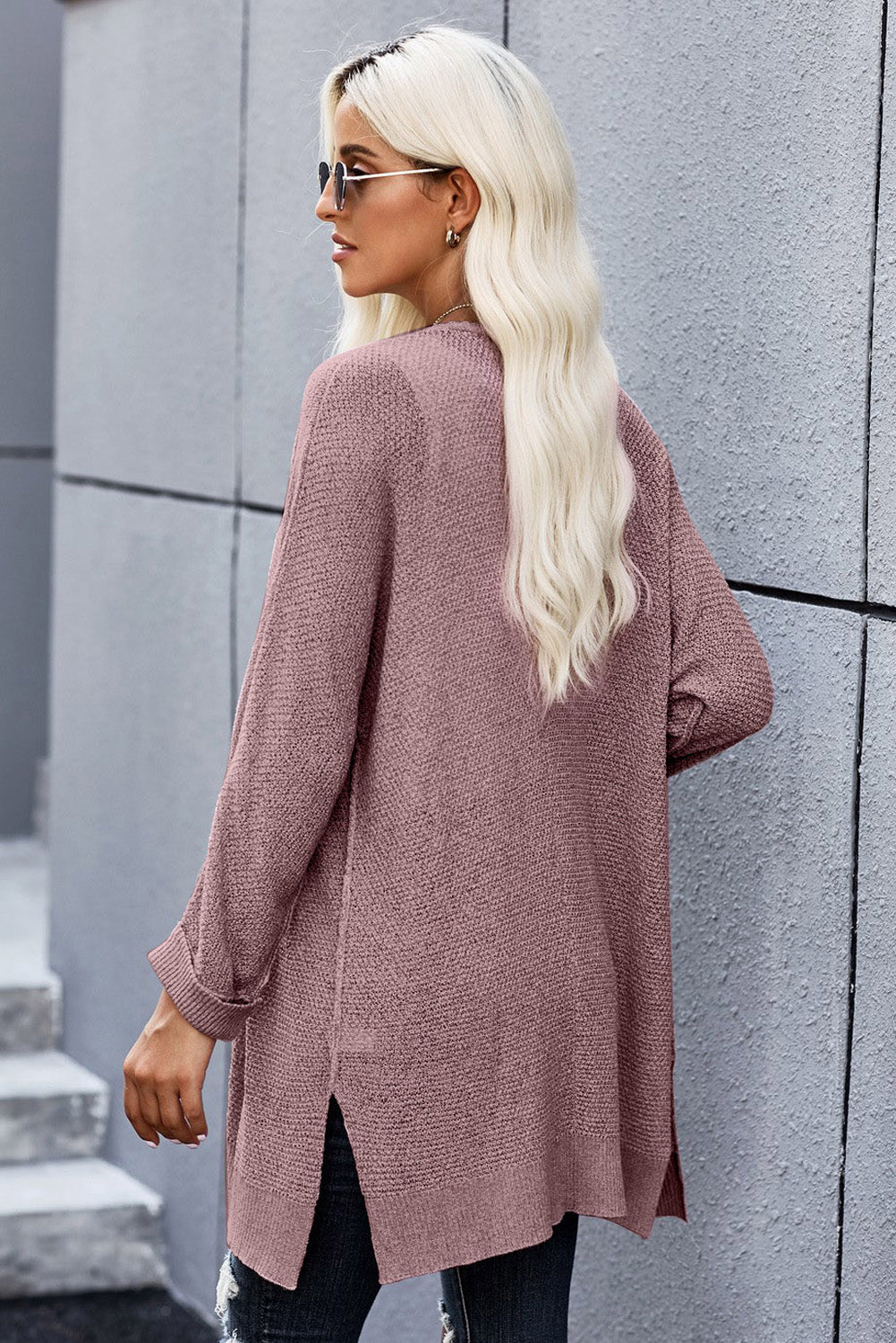 A stylish pink solid color loose fit open front knitted cardigan with cuffed long sleeves, perfect for layering over outfits.